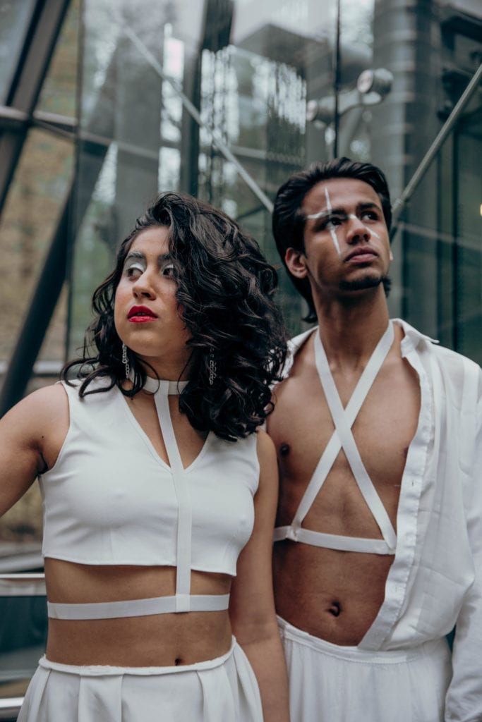 Cherie and Saad wearing all white eco-friendly, recycled outfits to combat fast fashion in a glass structure in Canary Wharf