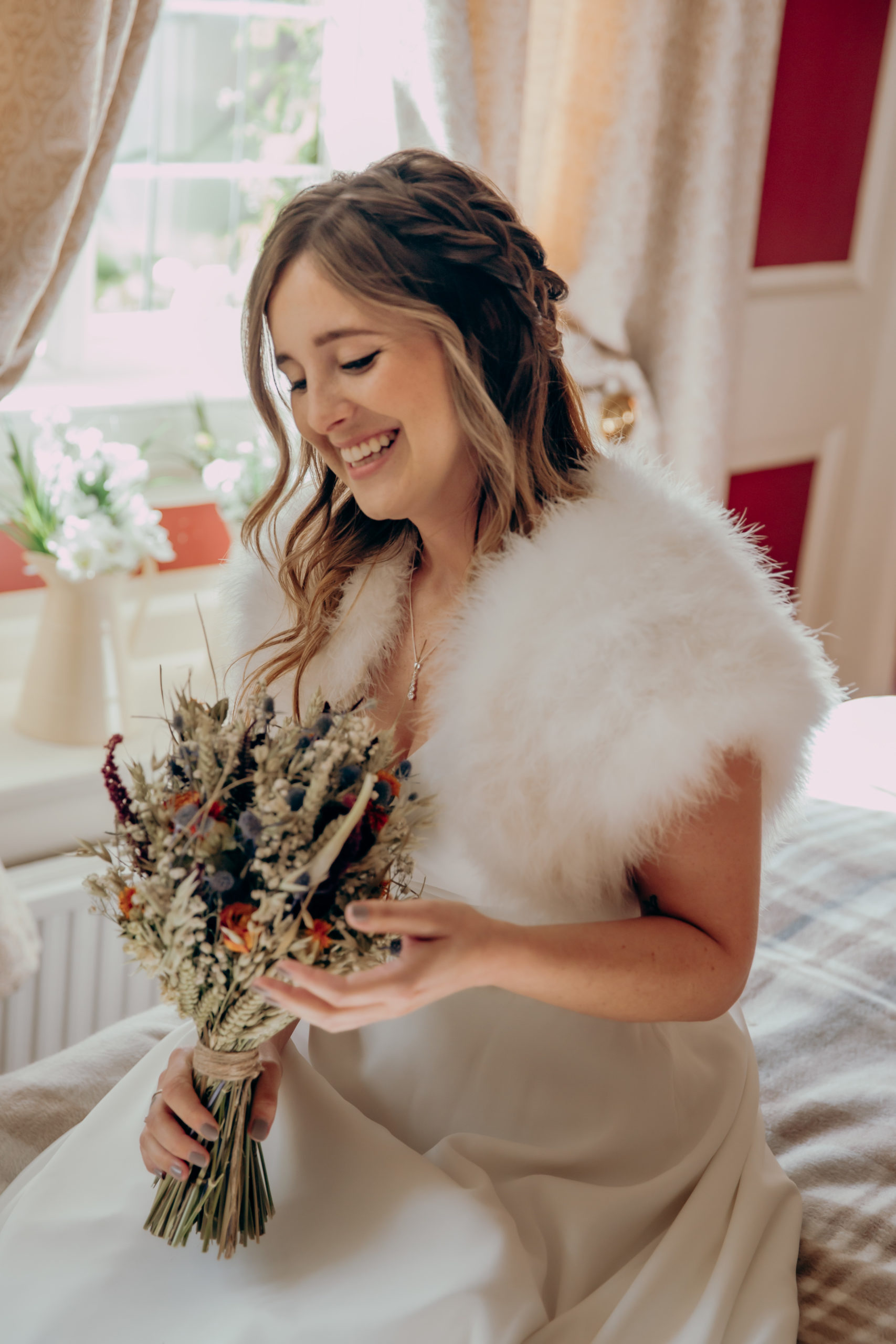 Lisa sits in her room as she finishes getting ready, laughing and holding her bouquet