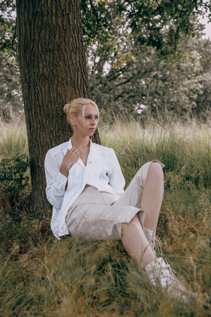 Amber wearing sustainable cream trousers and white blouse in Richmond Park, London
