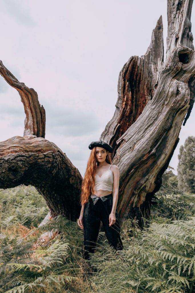 Jasmine wearing black trouser and a white bralet with a black beret in Richmond Park, London
