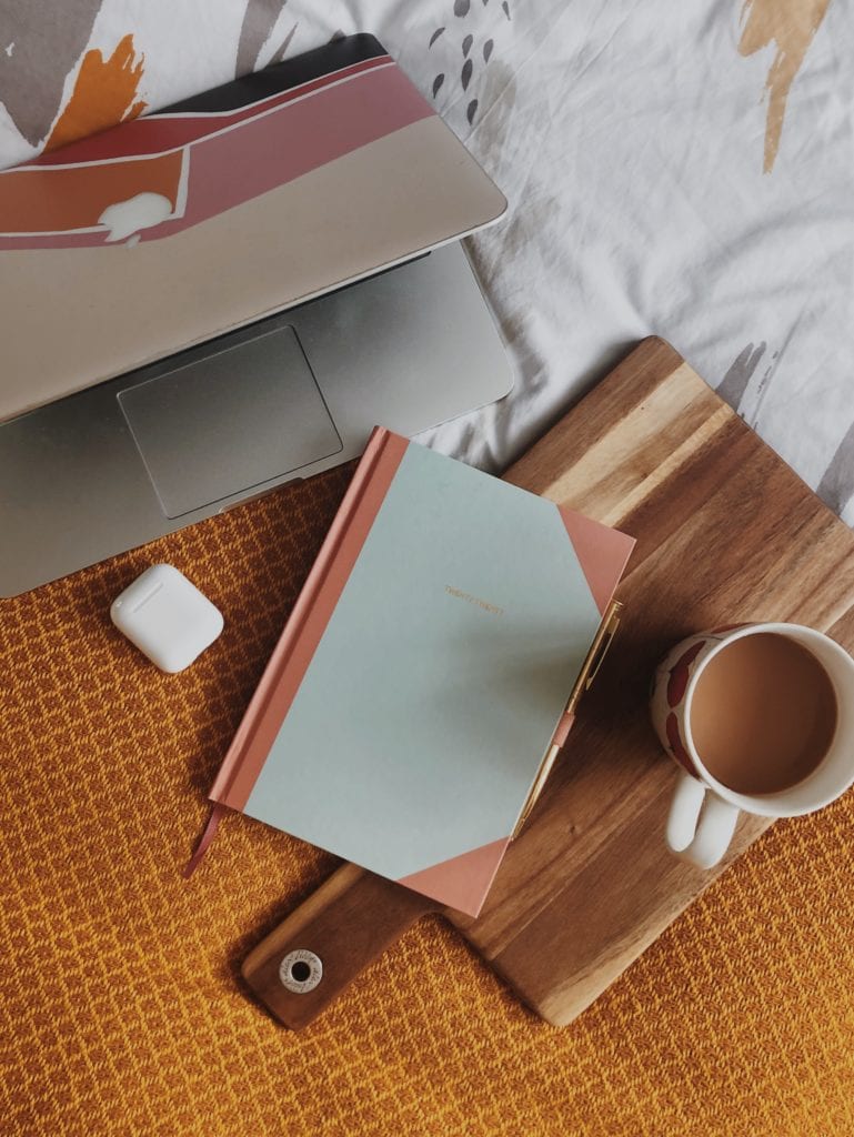 An office style flatlay of my bed with laptop and stationery