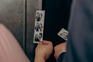 Guests holding photobooth strips of the bride and groom