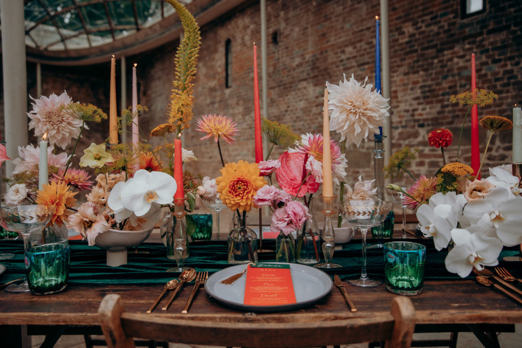 A table setup with jewel coloured tableware and flowers, perfect for a microwedding