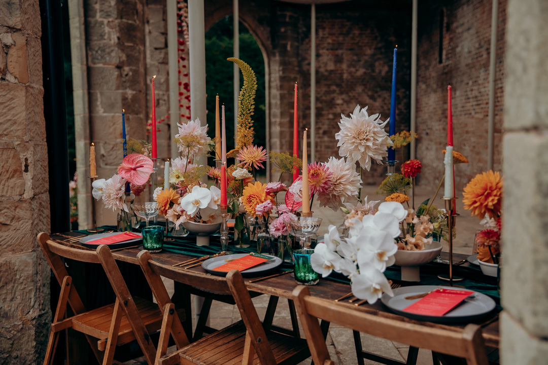 A table setup with jewel coloured tableware and flowers