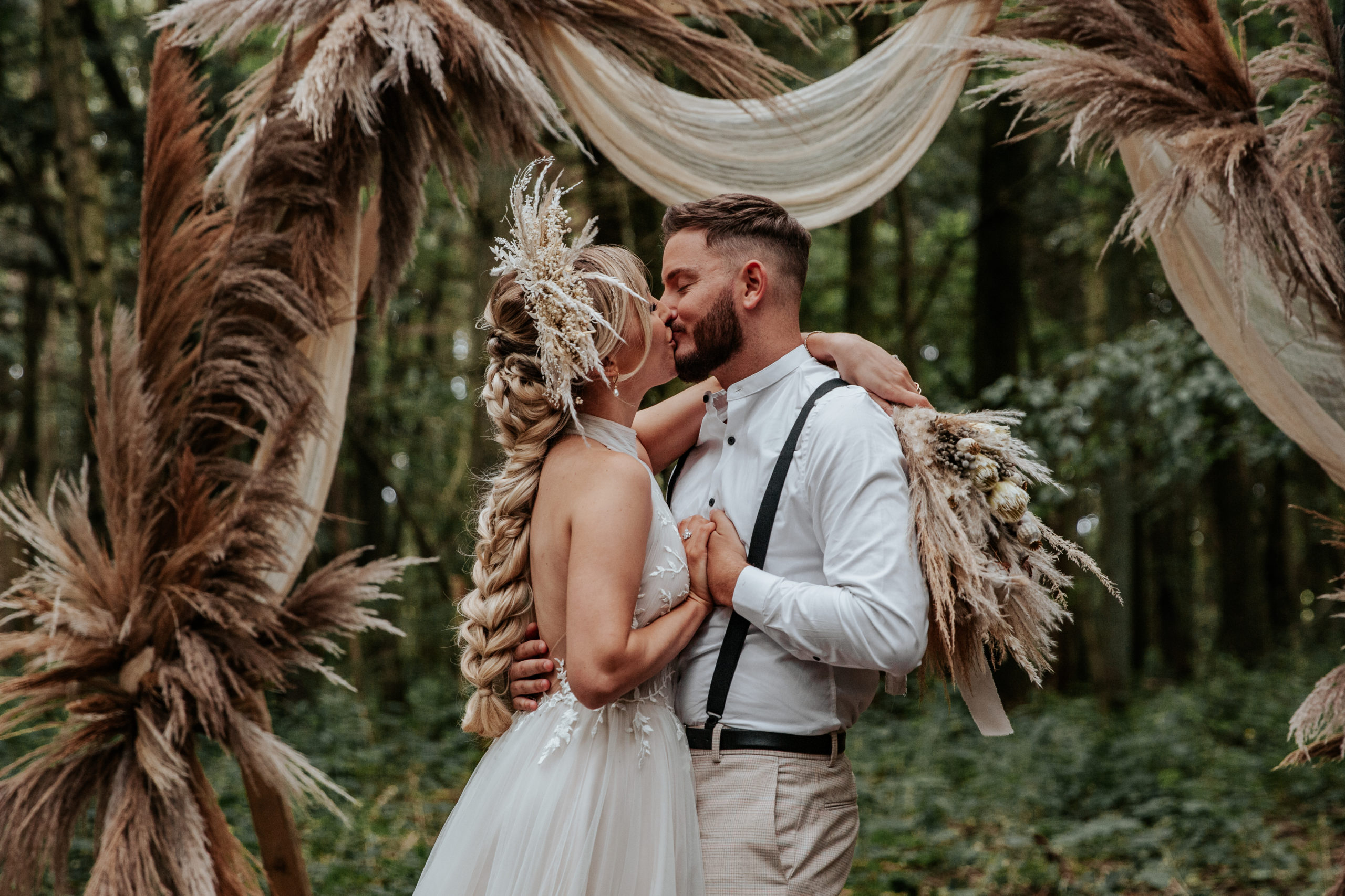 Will and Jessica kiss infront of their woodland altar at Longton Wood