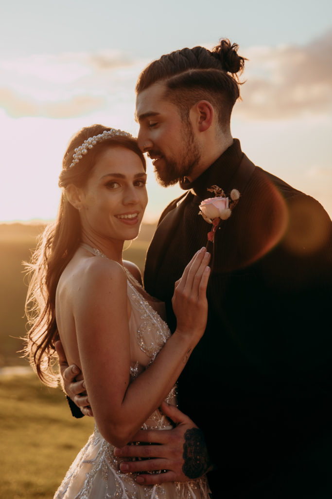 Tomina and Jacob embrace out in the gardens of Botley Hill Barn in golden hour