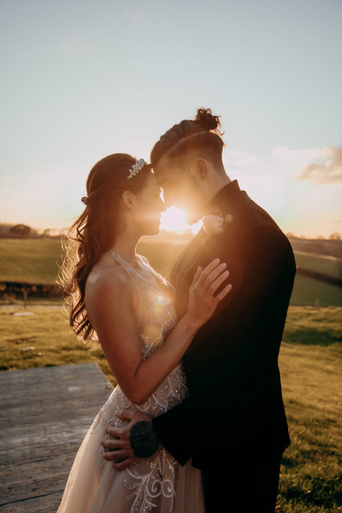 Tomina and Jacob embrace out in the gardens of Botley Hill Barn in golden hour
