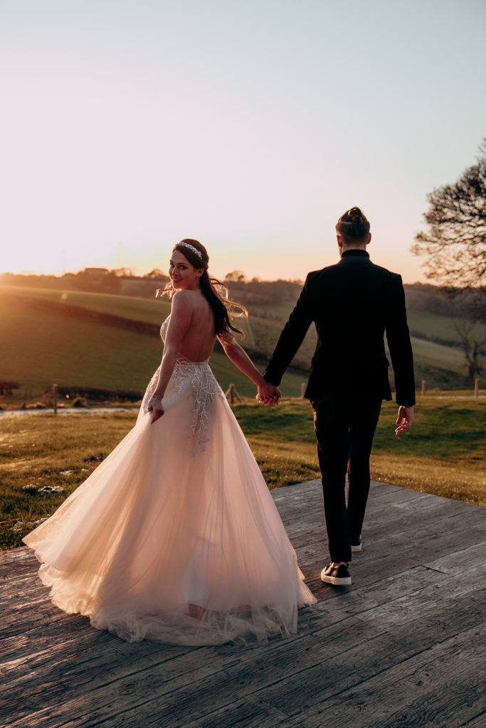 Tomina and Jacob walk away towards the gardens of Botley Hill Barn in golden hour