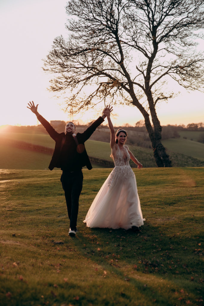 Tomina and Jacob cheer and celebrate out in the gardens of Botley Hill Barn in golden hour