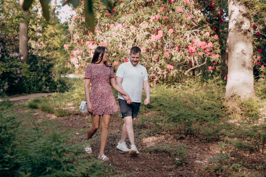 Izi and Rob walking along together through the forest at golden hour, during their engagement shoot