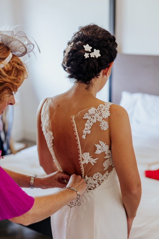 Bride having the buttons done up on her floral lace wedding dress