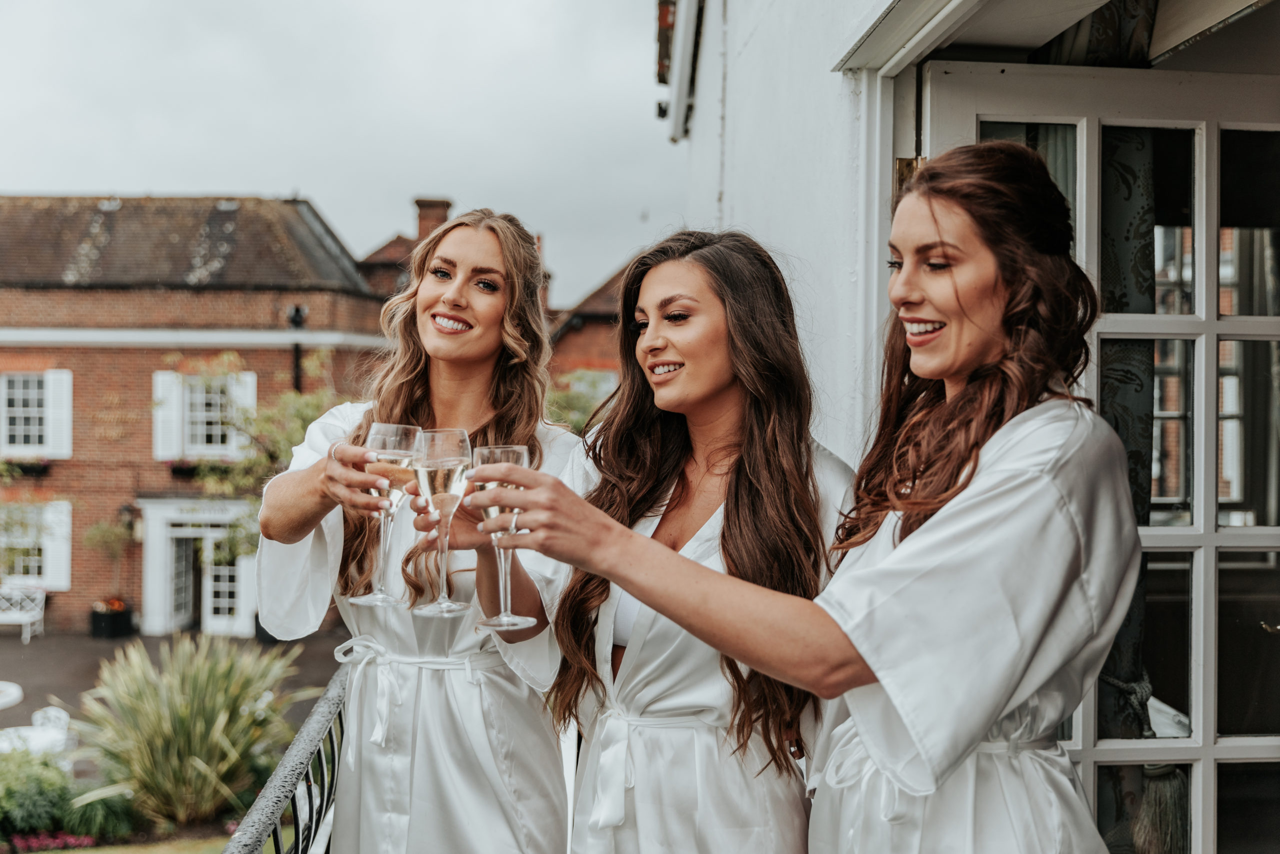 Emma and her sisters cheers prosecco on the balcony in their matching dressing gowns during their getting ready photos