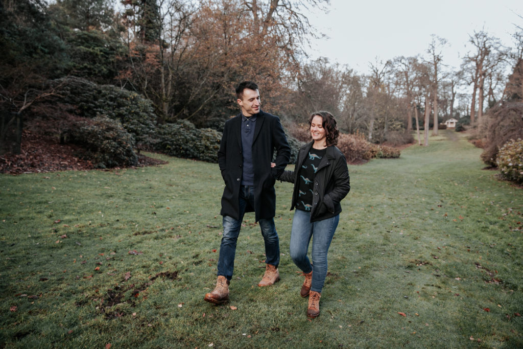 Laura and Stuart walk along the frosty grass during their winter engagement shoot