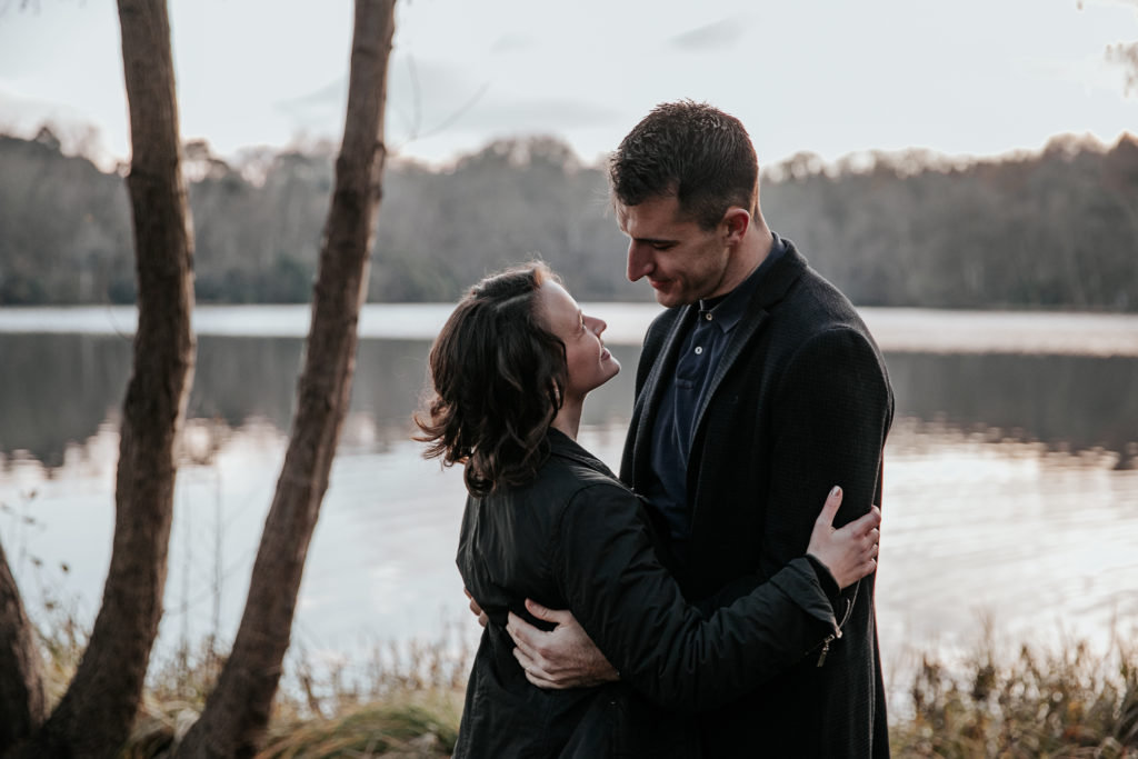 Laura and Stuart embrace infront of Virginia Waters lake on their engagement shoot