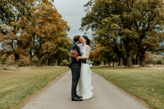 Kirsty & Aldous kiss in the middle of Ufton Court's long drive lined by tall trees