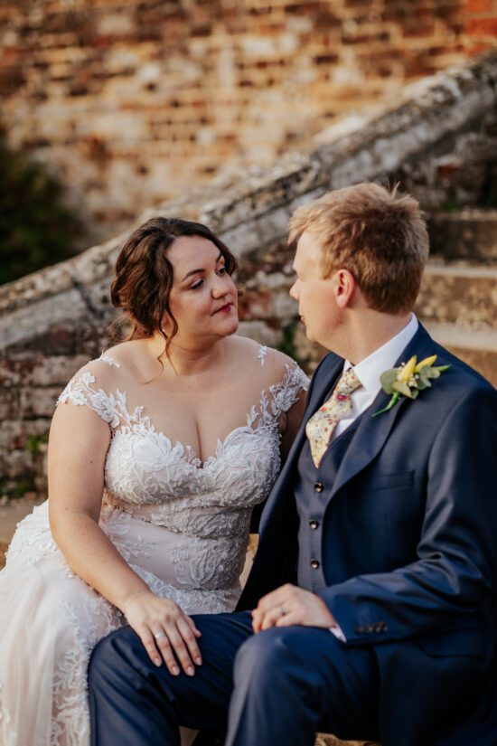 Bride and groom sit together on the stone stairs at Ufton Court at Sunset