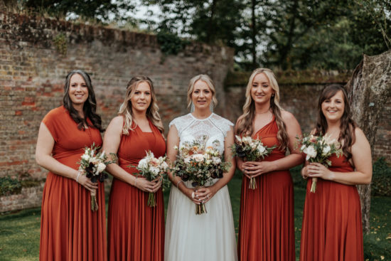 Rachael stands with her bridesmaids in the grounds of Ufton Court. Rachael is in a wedding dress while her bridesmaids where terracotta coloured dresses
