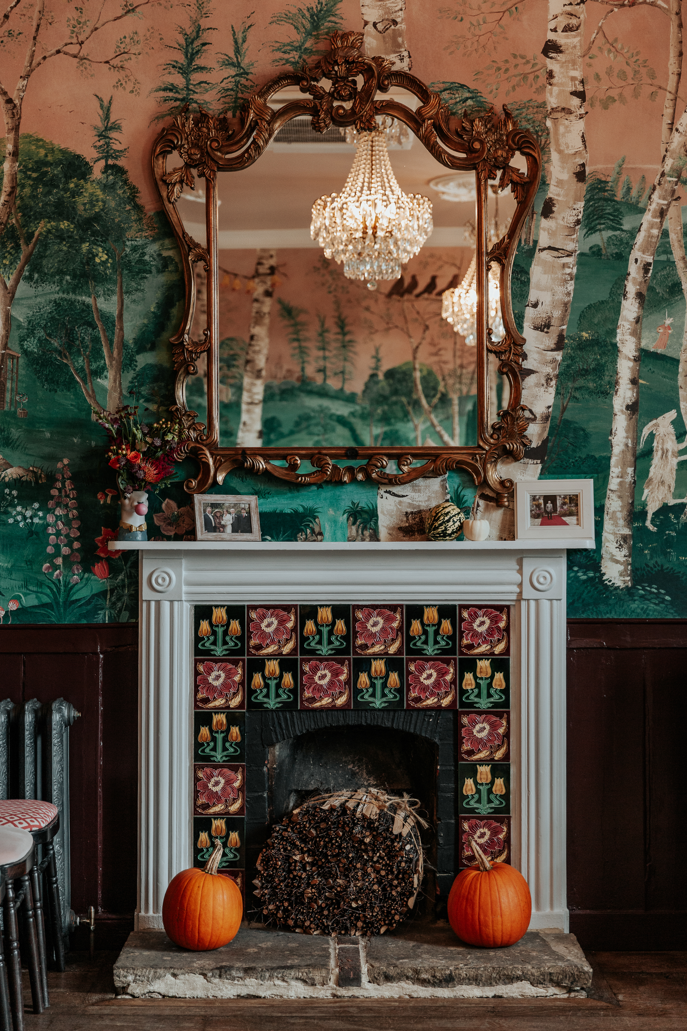 A fireplace decorated with pumpkins and autumnal flowers