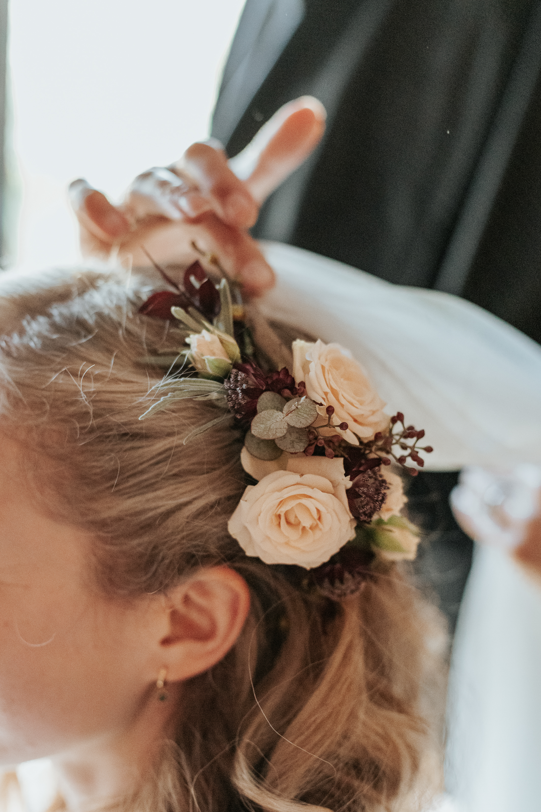 Maddie's veil being put in, next to her fresh flower hair clip