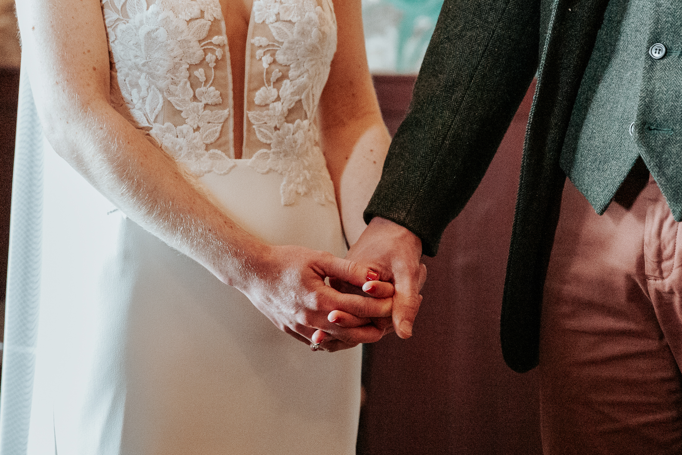 A close up shot of Maddie and Will's hands clasped together during their wedding ceremony