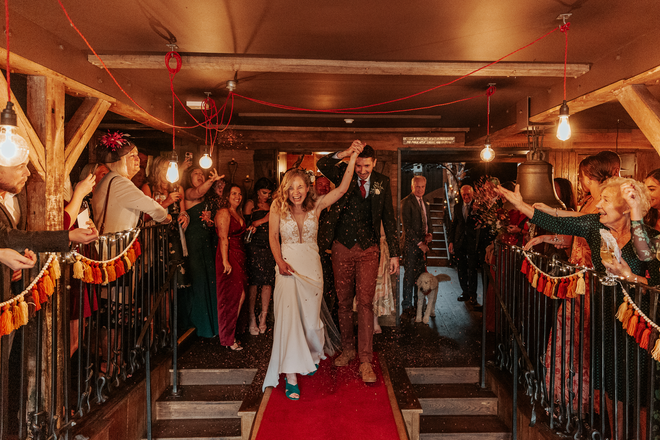 Maddie and Will walk down the long table at The Bell in Ticehurst, while their guests throw confetti over them