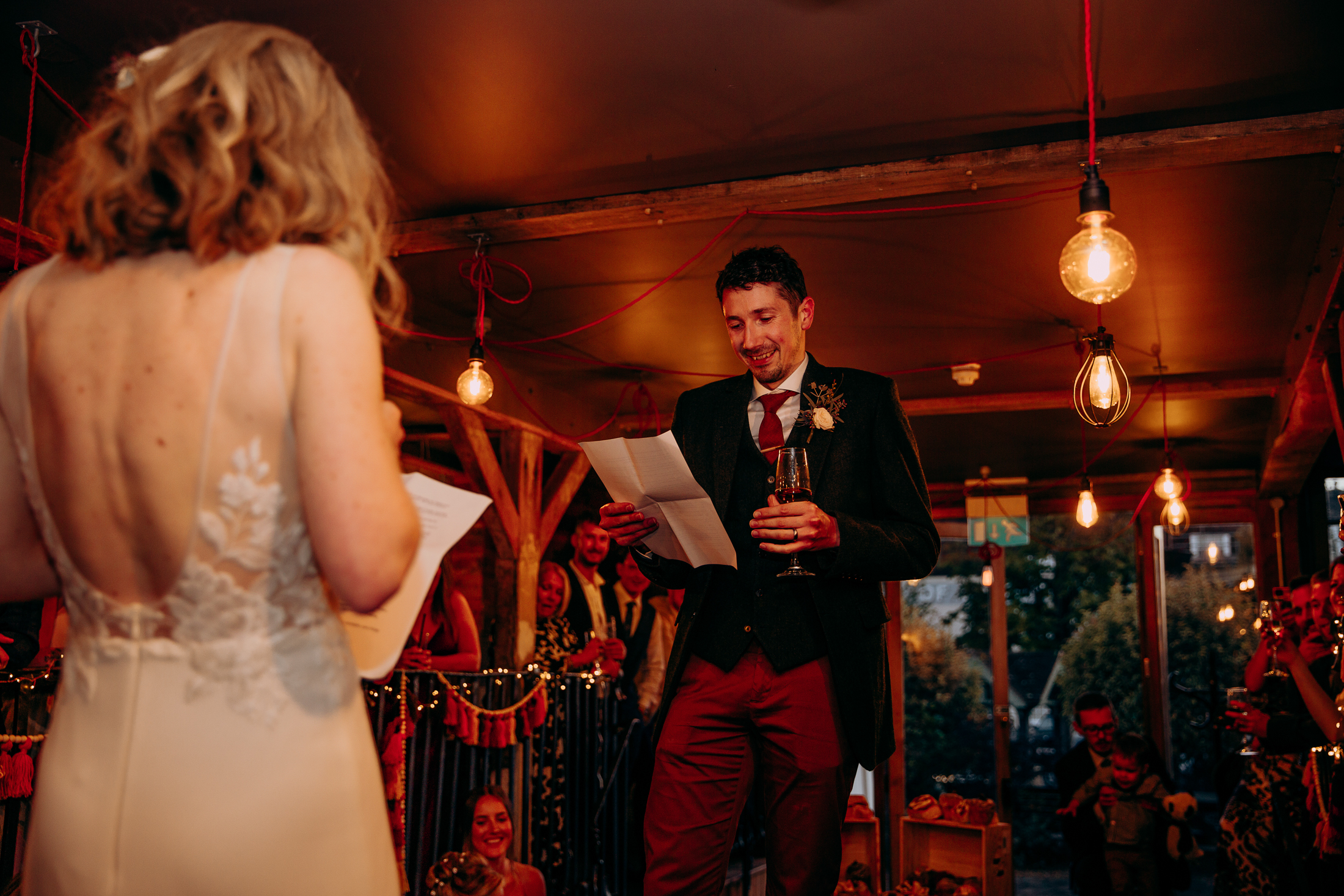 Maddie and Will face eachother during their wedding speech, stood on the long table at The Bell in Ticehurst