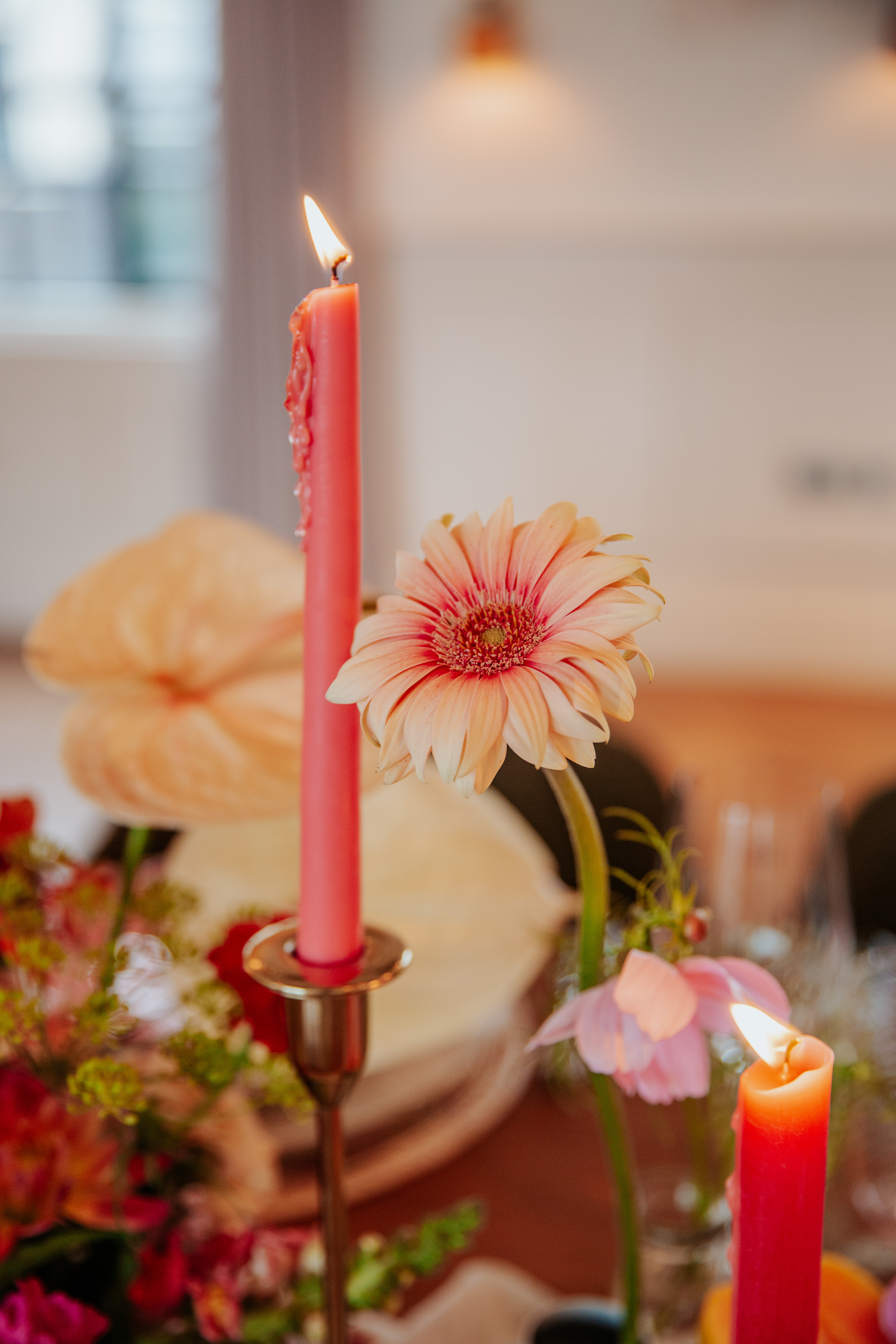A close up shot of a pink flower and candle on a table in Mortimer House's gallery