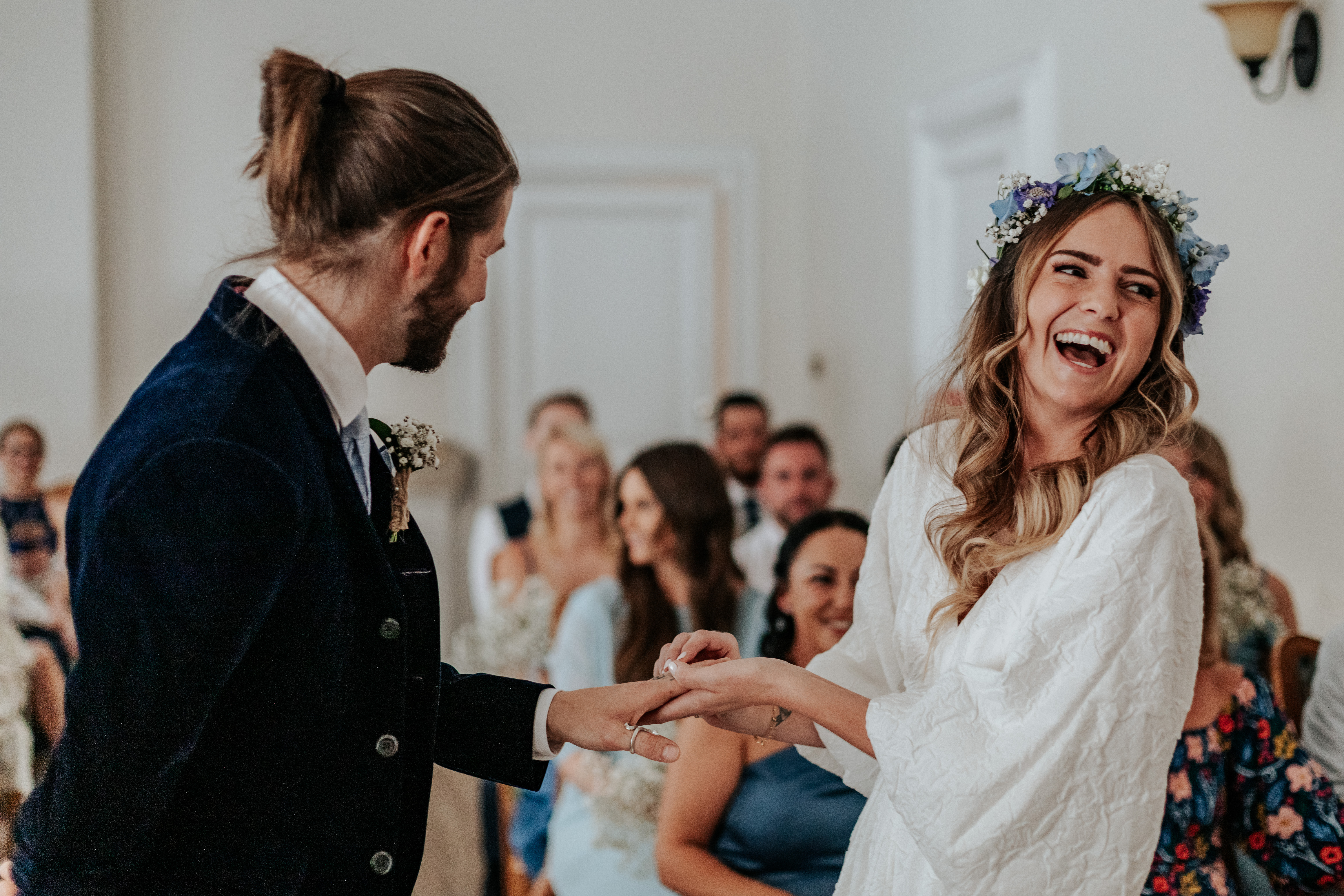 HannahSam25_07-064 Bride laughs as she puts a wedding ring on the Groom's finger