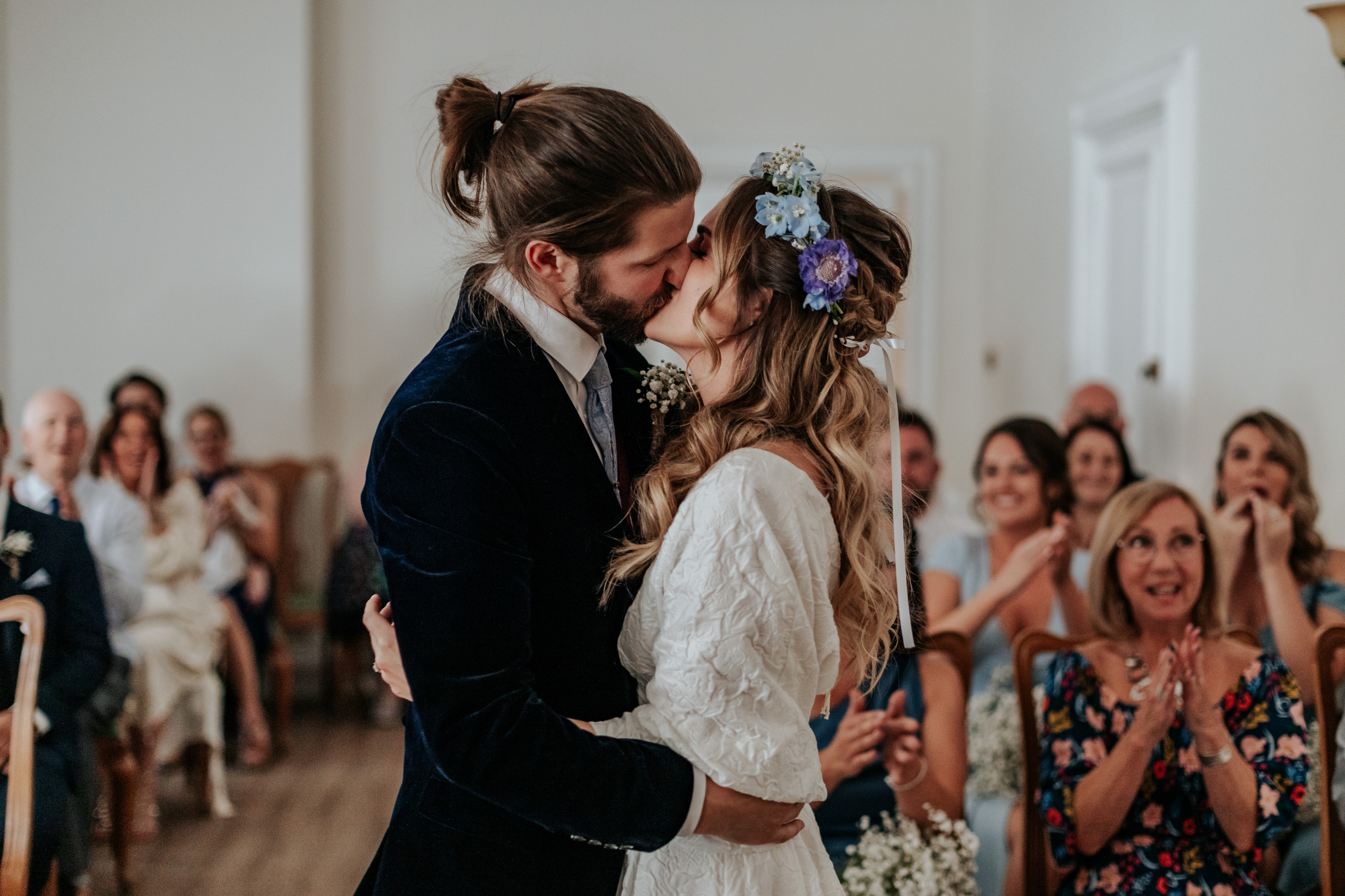 HannahSam25_07-070 Bride and groom kiss while the crowd claps and whistles in the background