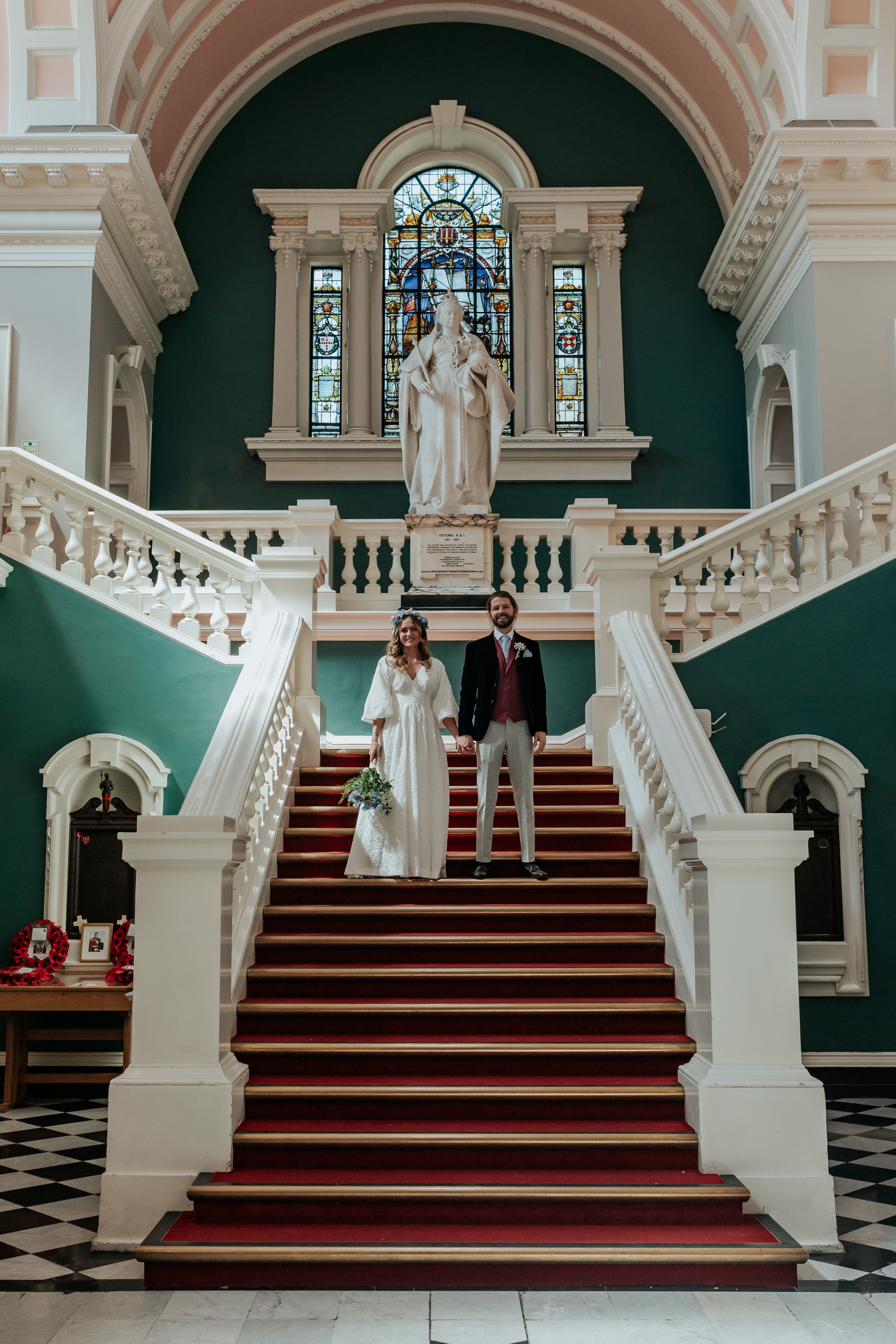 HannahSam25_07-114 Bride and groom stood holding hands on the stairs of Woolwich Town hall during their London wedding