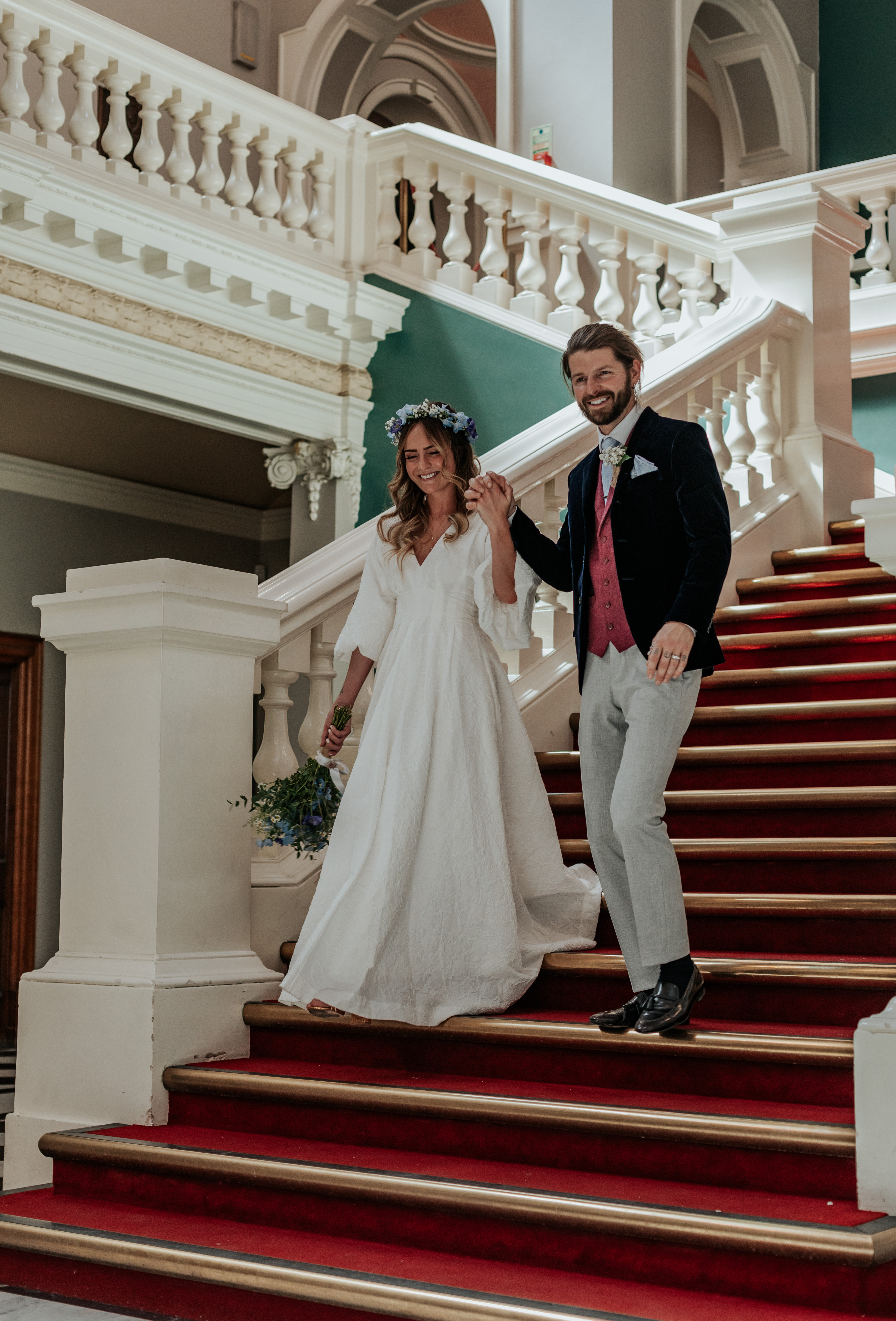 HannahSam25_07-119 Bride and groom walk down the stairs at Woolwich Town Hall while holding hands during their London wedding
