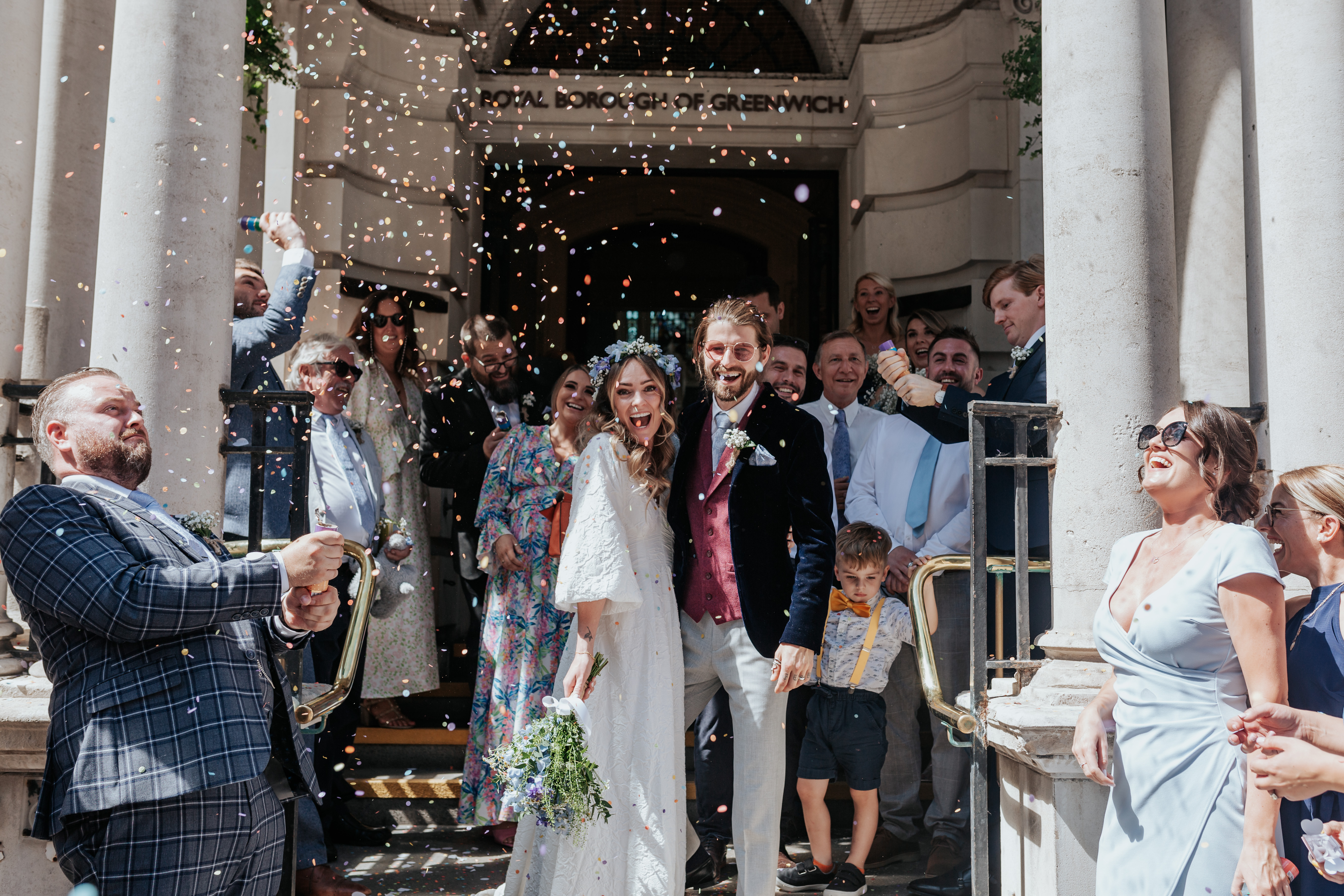 HannahSam25_07-128 Bride and groom stand outside Woolwich registry office as their guests throw confetti over them