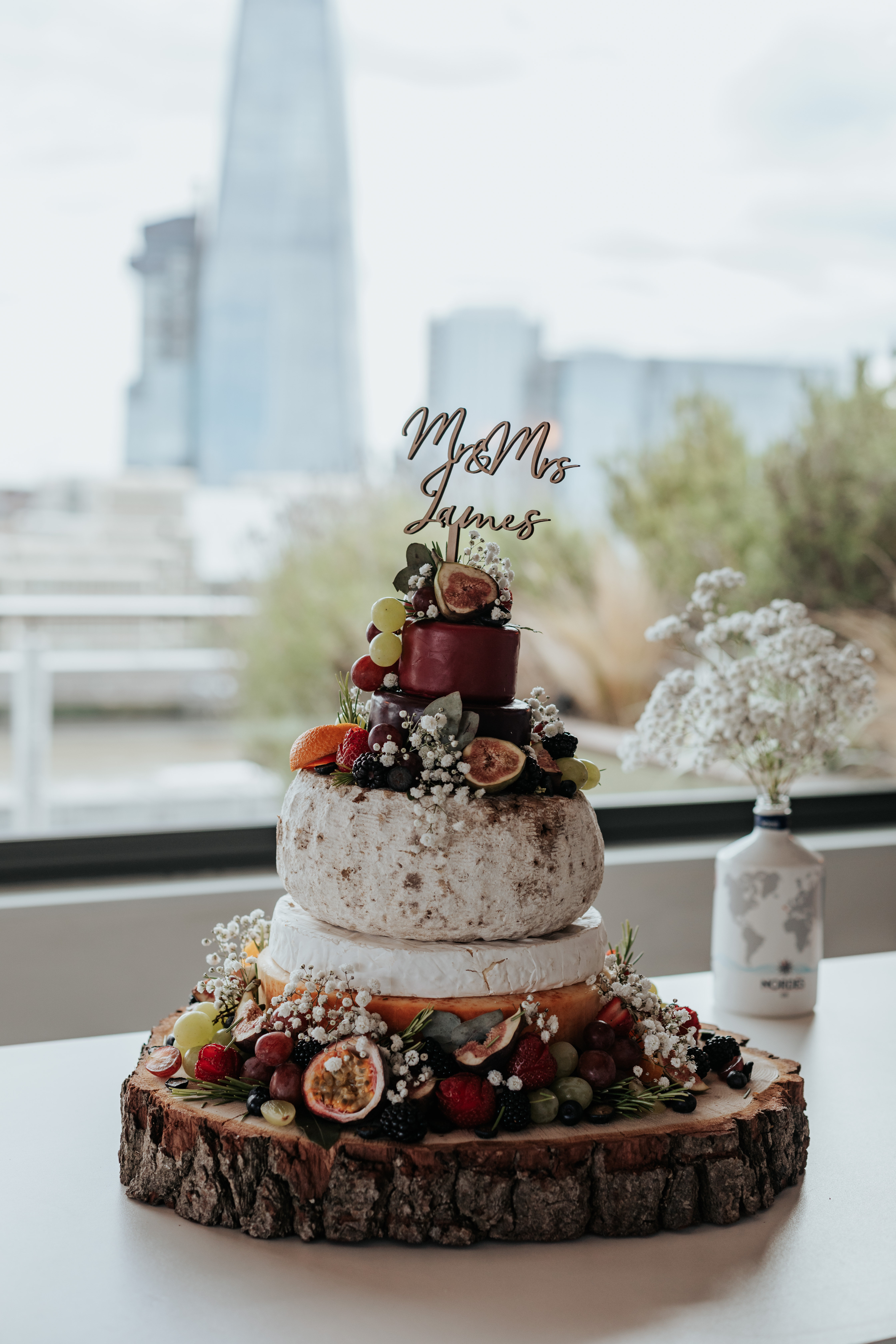 HannahSam25_07-152 A cheese wedding cake with a 'Mr & Mrs James' cake topper, with the London skyline in the background