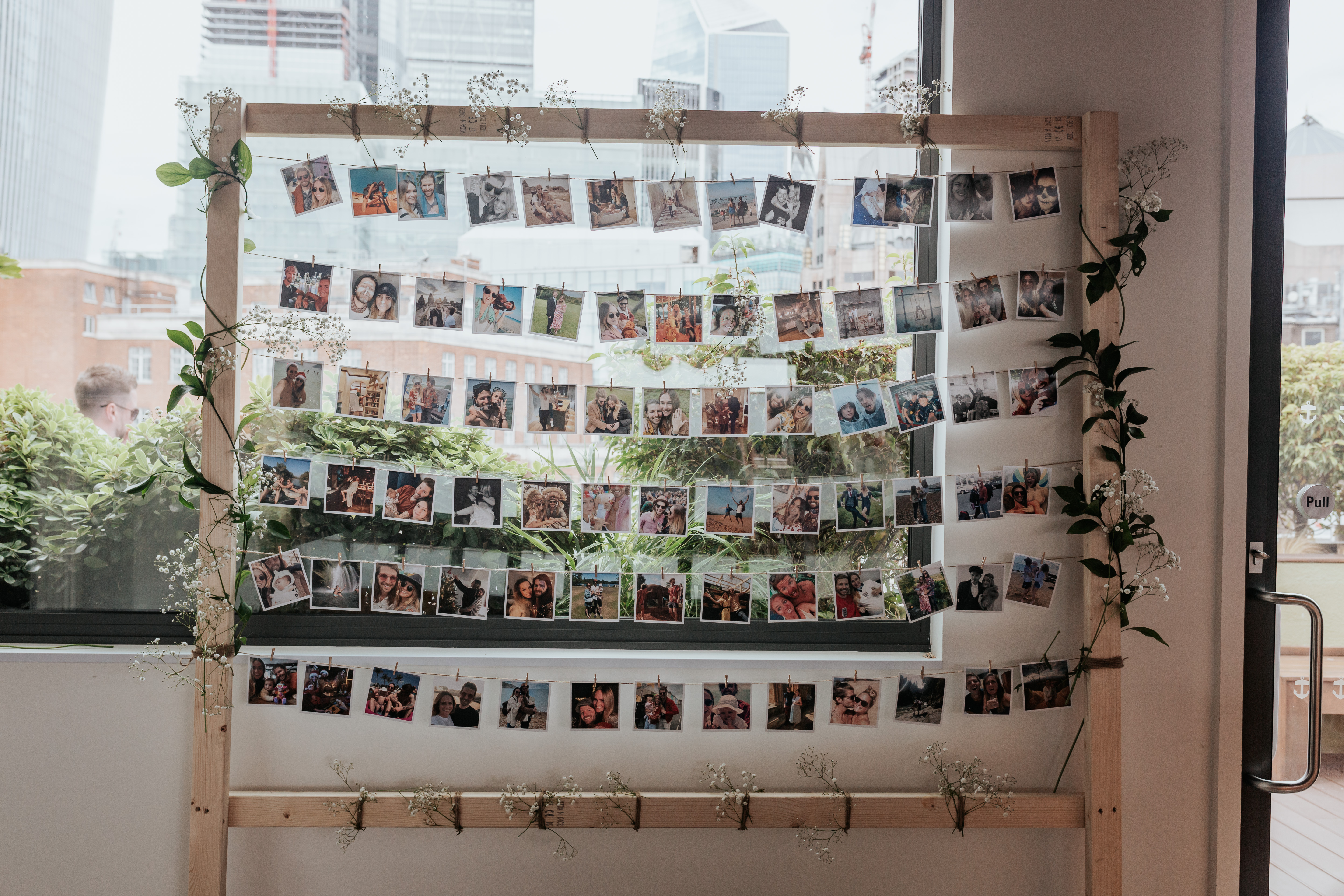 HannahSam25_07-158 A large wooden frame holding rows of polaroid photos