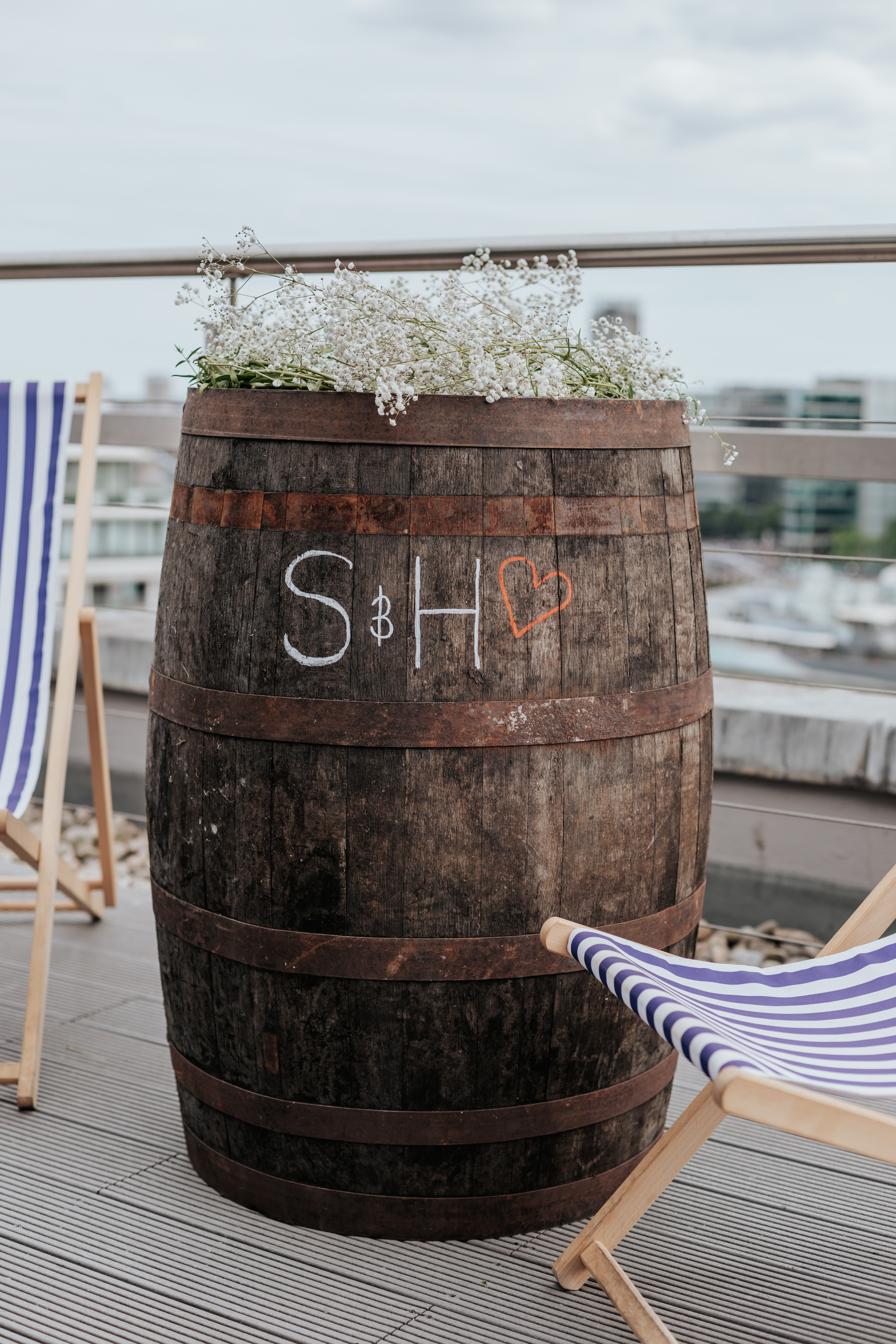 HannahSam25_07-163 Some deck chairs and a wooden barrel with 'S & H' written on it, with gypsophila on top