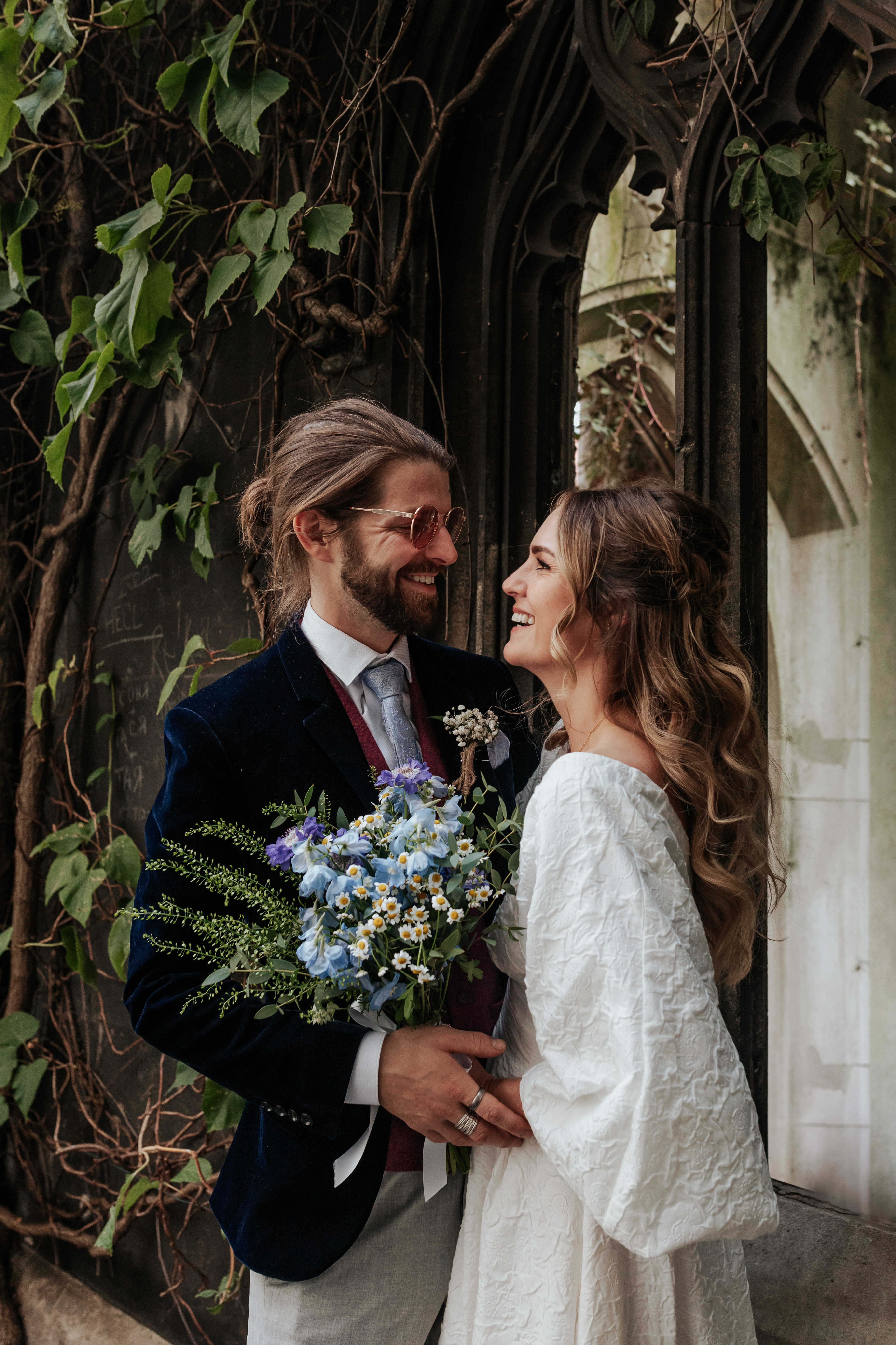 HannahSam25_07-256 Bride and groom stand in one of the windows at St Dunstans in The East gardens