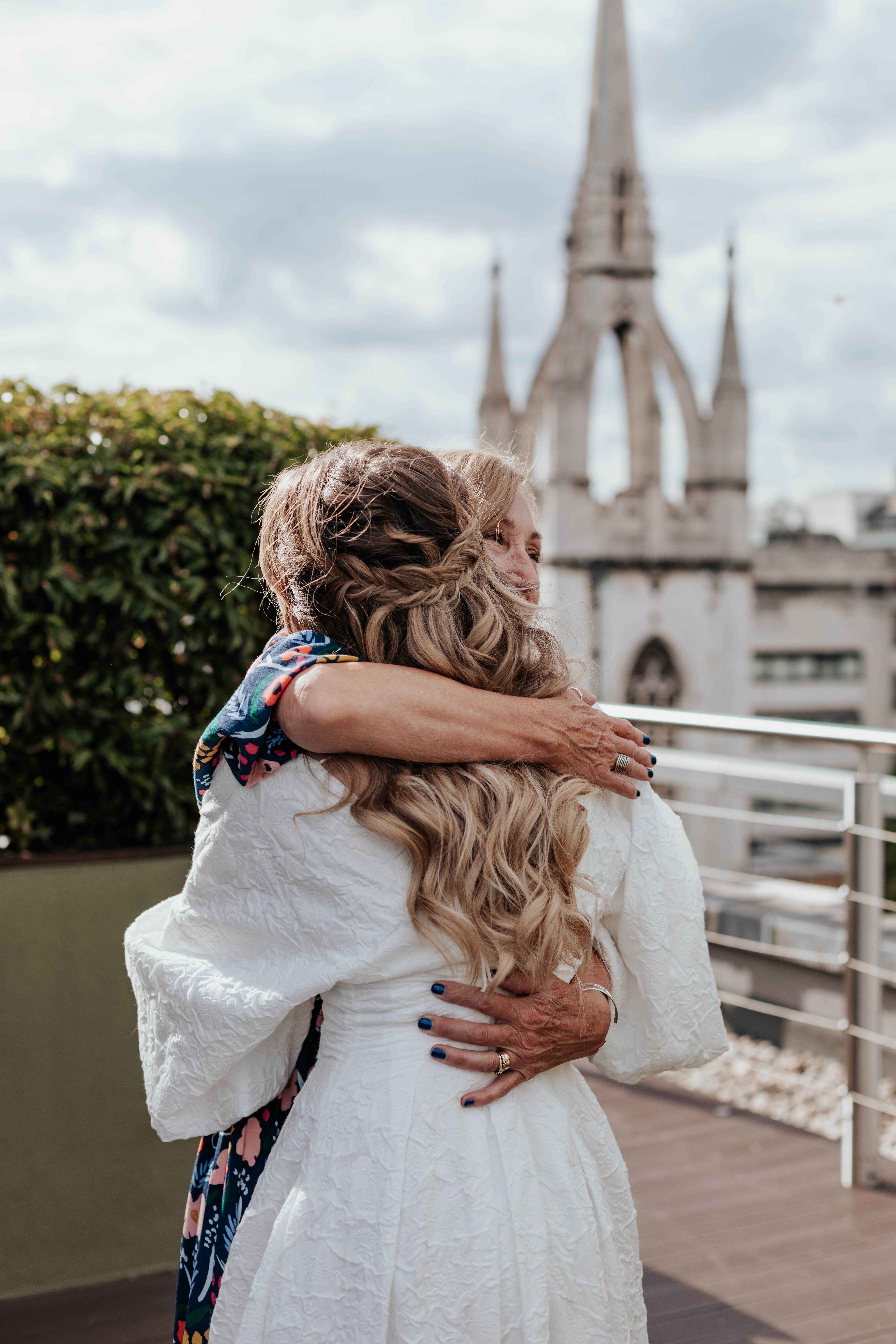 HannahSam25_07-307 Bride and her mum hug with the London city skyline in the background