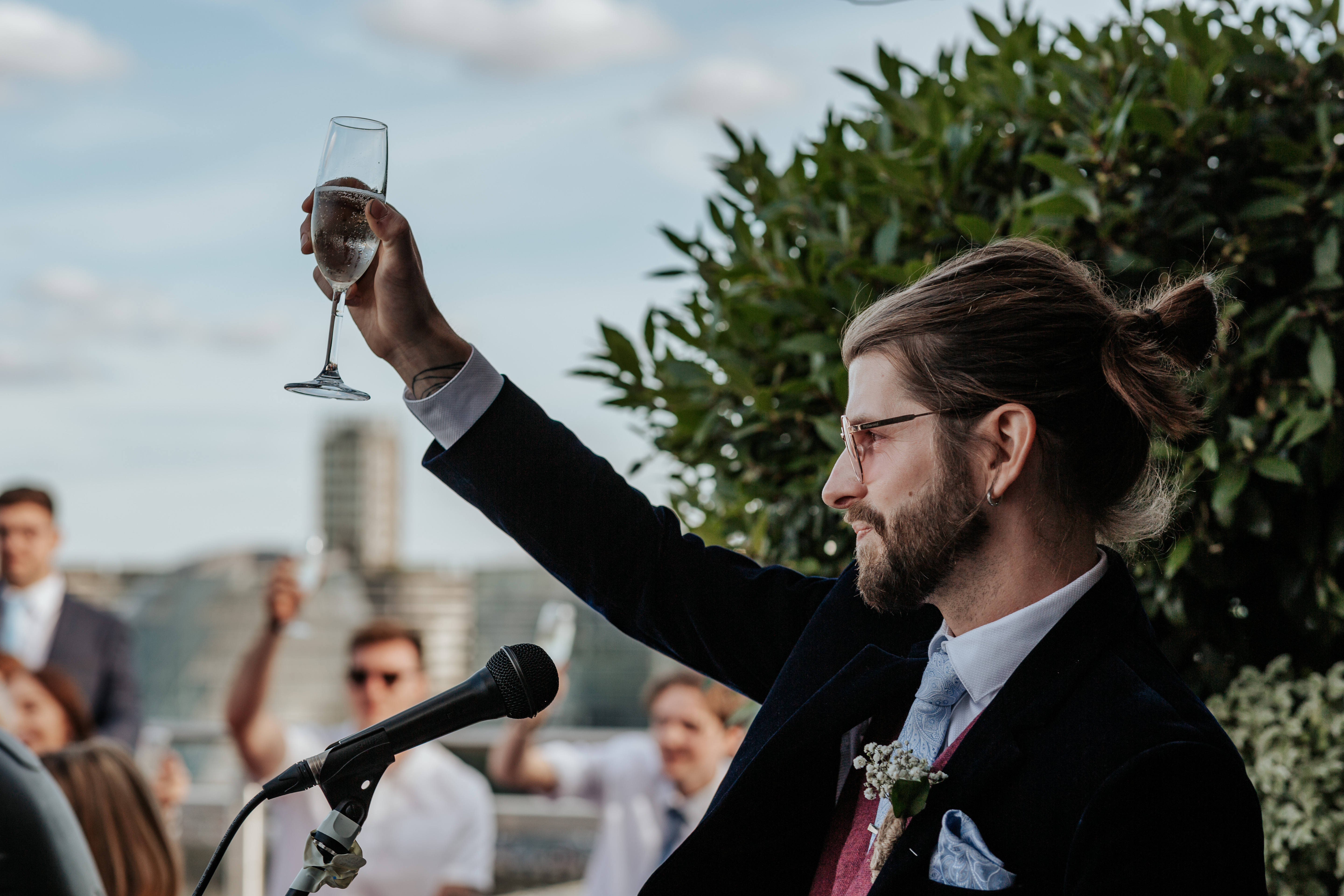 HannahSam25_07-403 Groom raises his glass during his speech on the rooftop terrace of a London bar