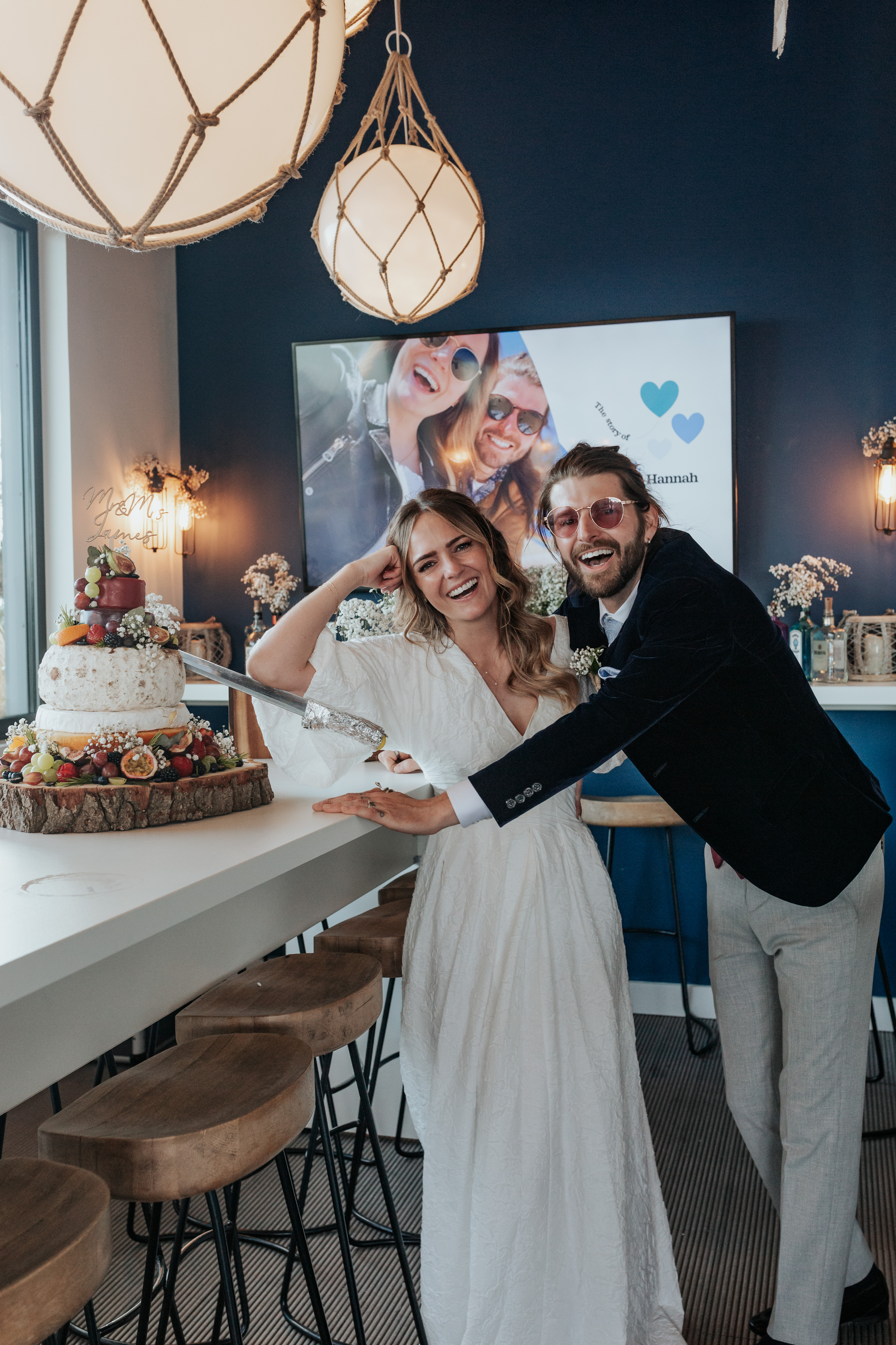 HannahSam25_07-445 Bride and groom laugh after a failed attempt at cutting their cheese wedding cake