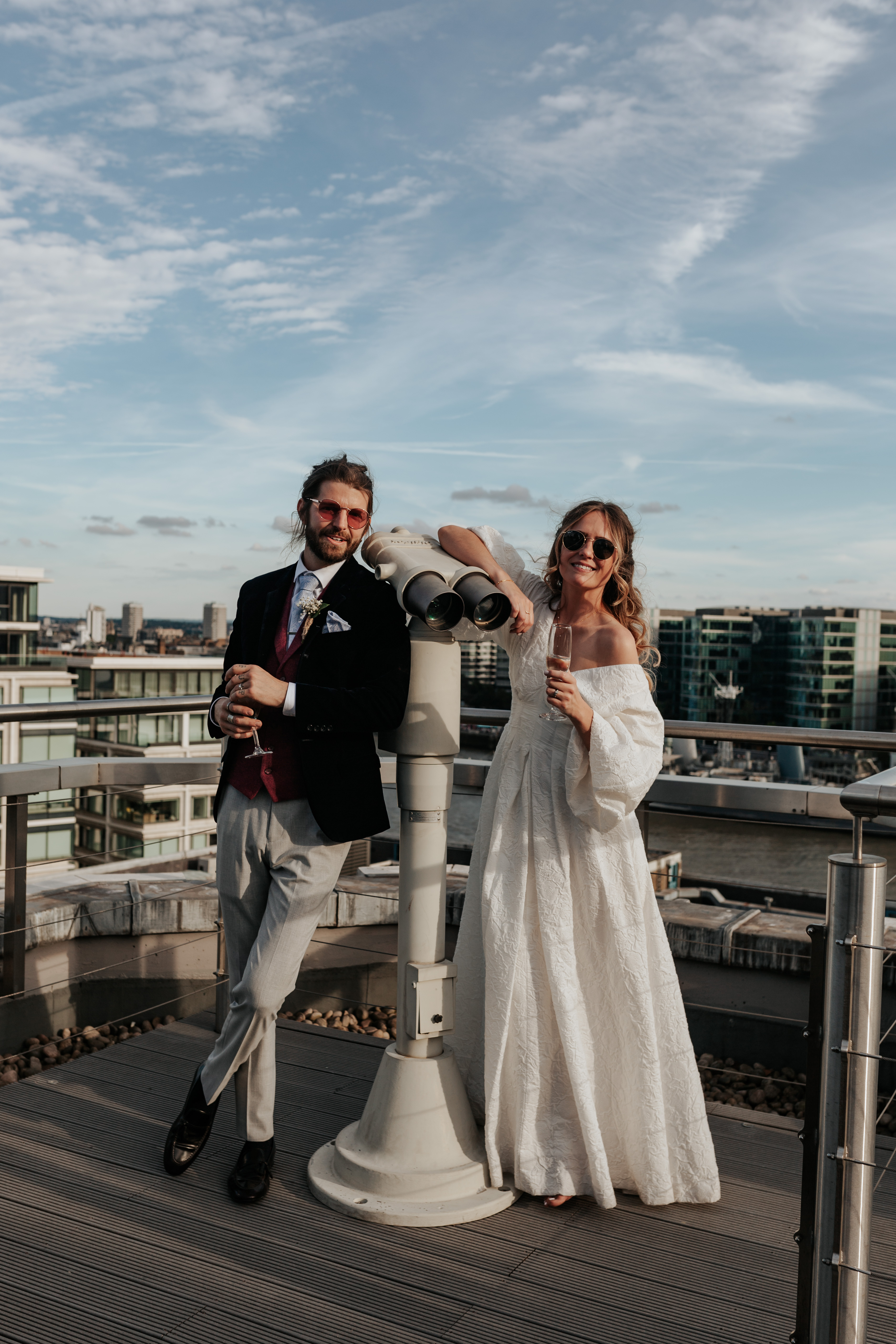 HannahSam25_07-466 Bride and groom post together on viewfinder binoculars on the rooftop terrace of a London bar