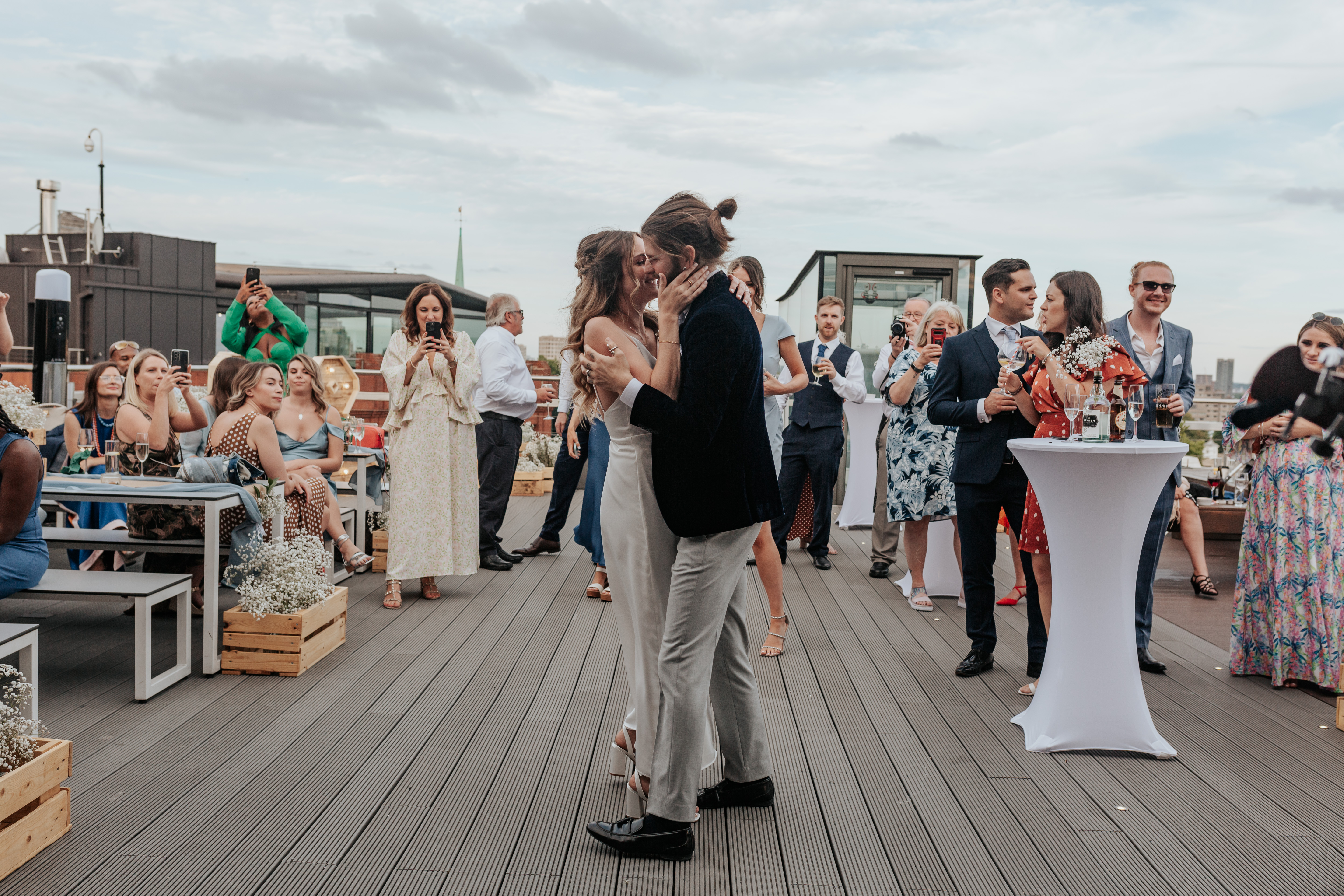 HannahSam25_07-541 Bride and groom kiss during their first dance on the rooftop terrace of a London bar