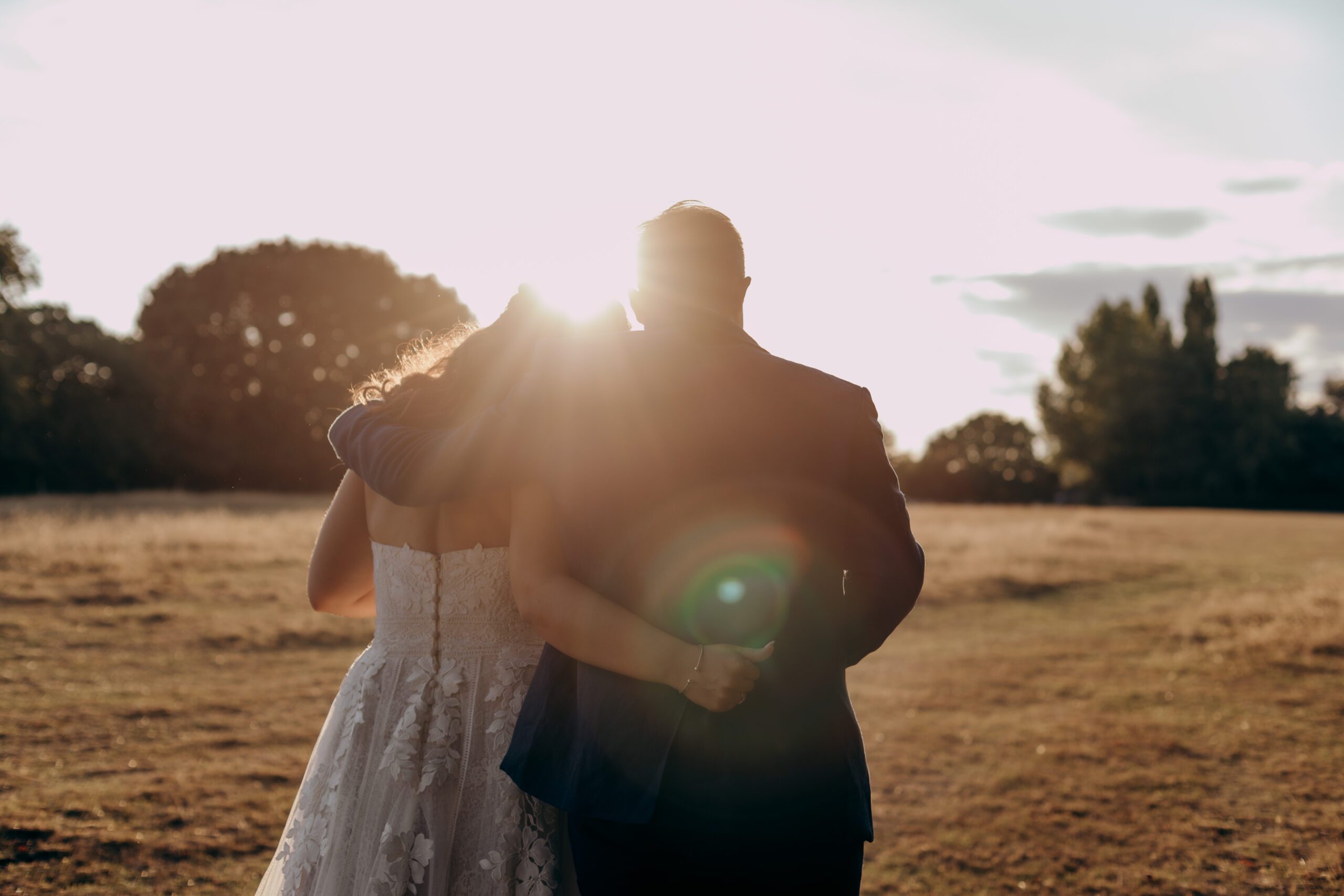 Bride and groom walking away with their arms round eachother during golden hour