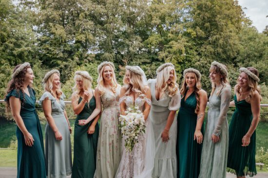 Bride and her bridesmaids wearing mismatched bridesmaids dresses in different shades of green