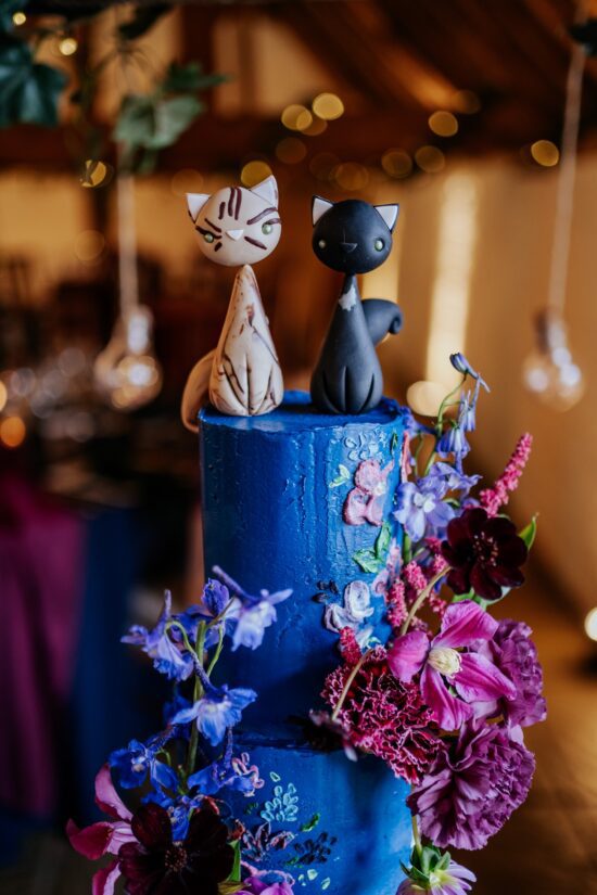 Fondant models of a tabby and black cats on top of a blue floral wedding cake