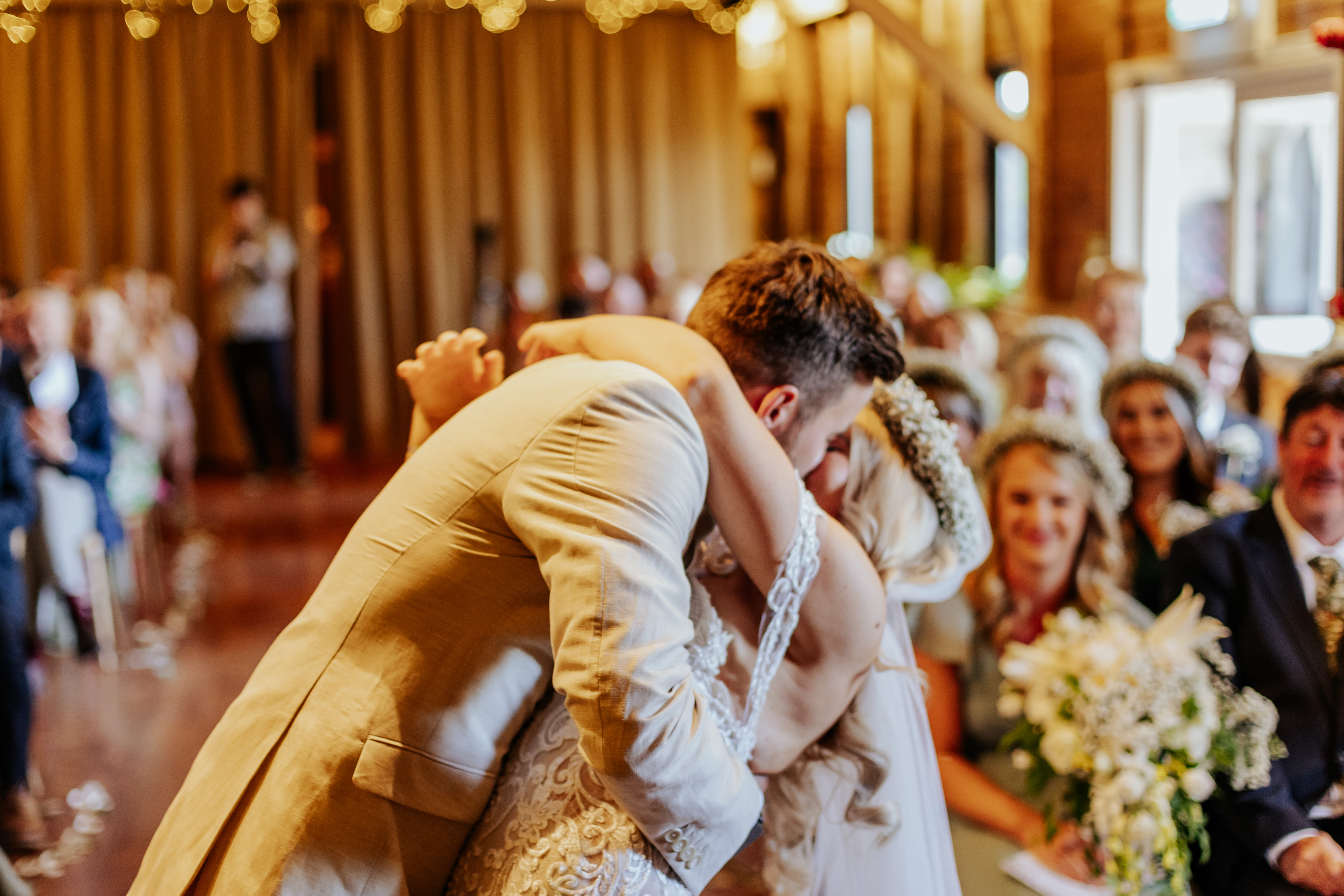 The groom dips the bride for their first kiss during the wedding ceremony