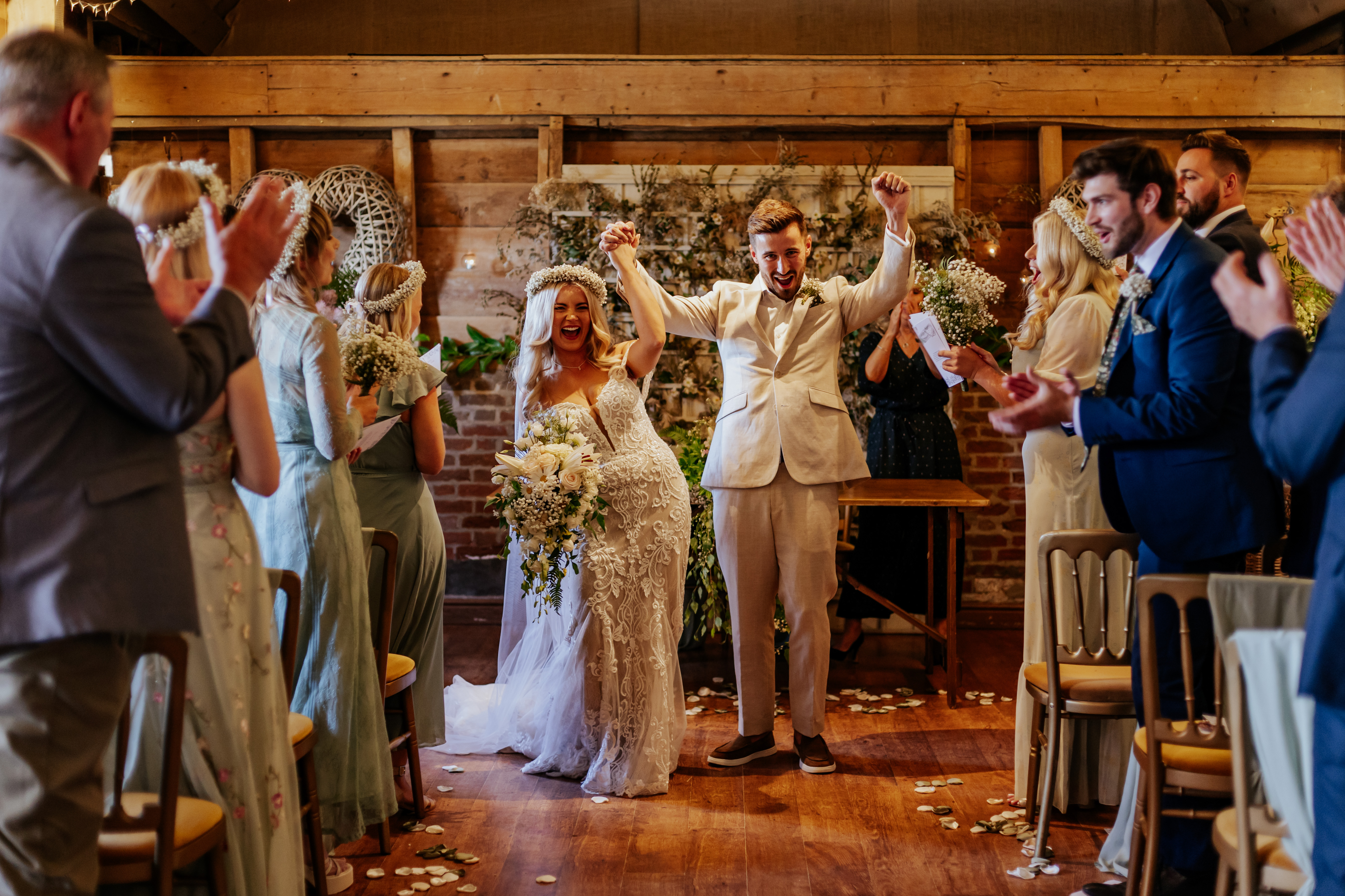 Bride and groom with their arms in the air after their wedding ceremony at Wellington Barn