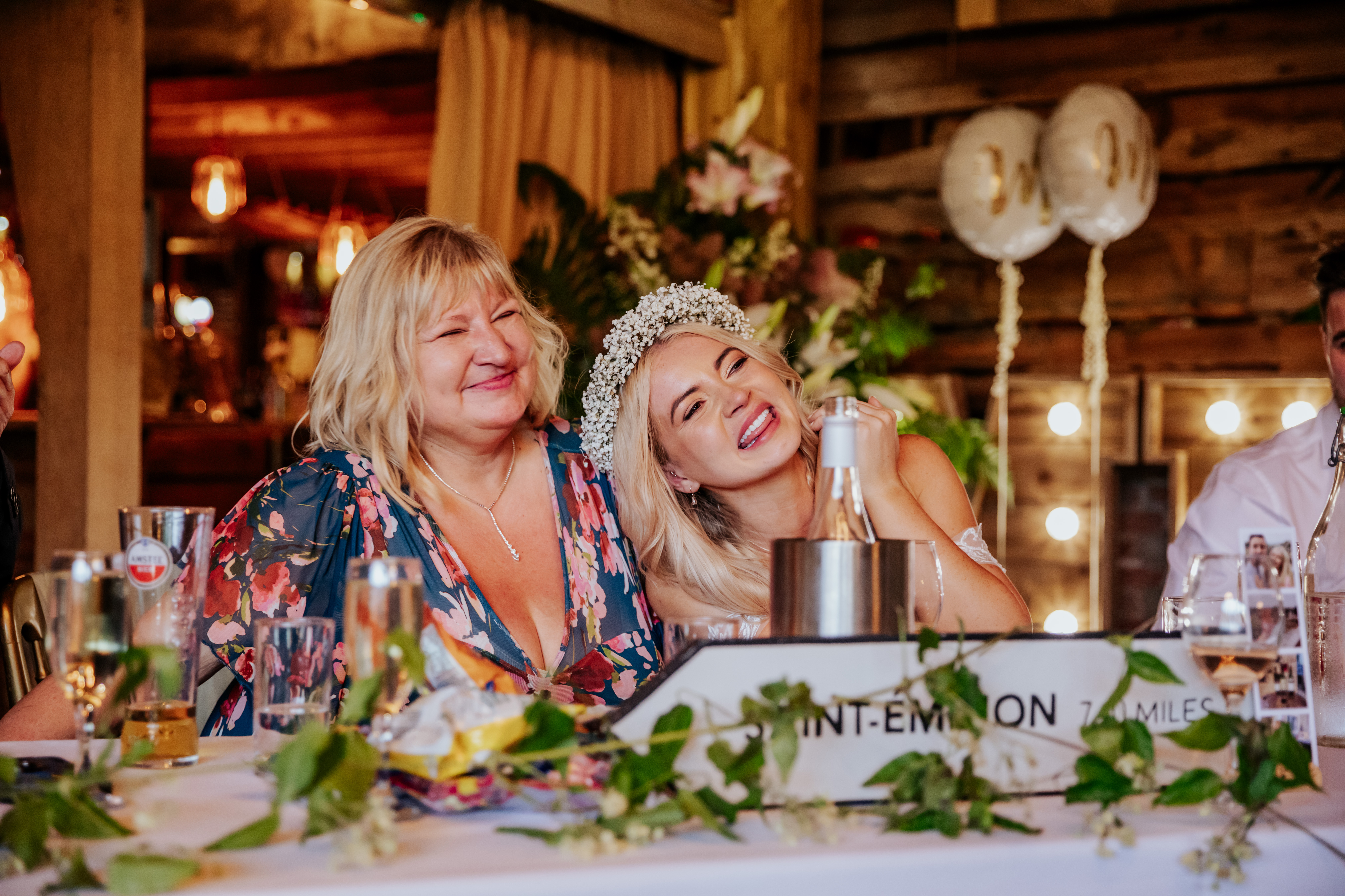 Teary bride smiles and leans on her mum's shoulders during the speeches