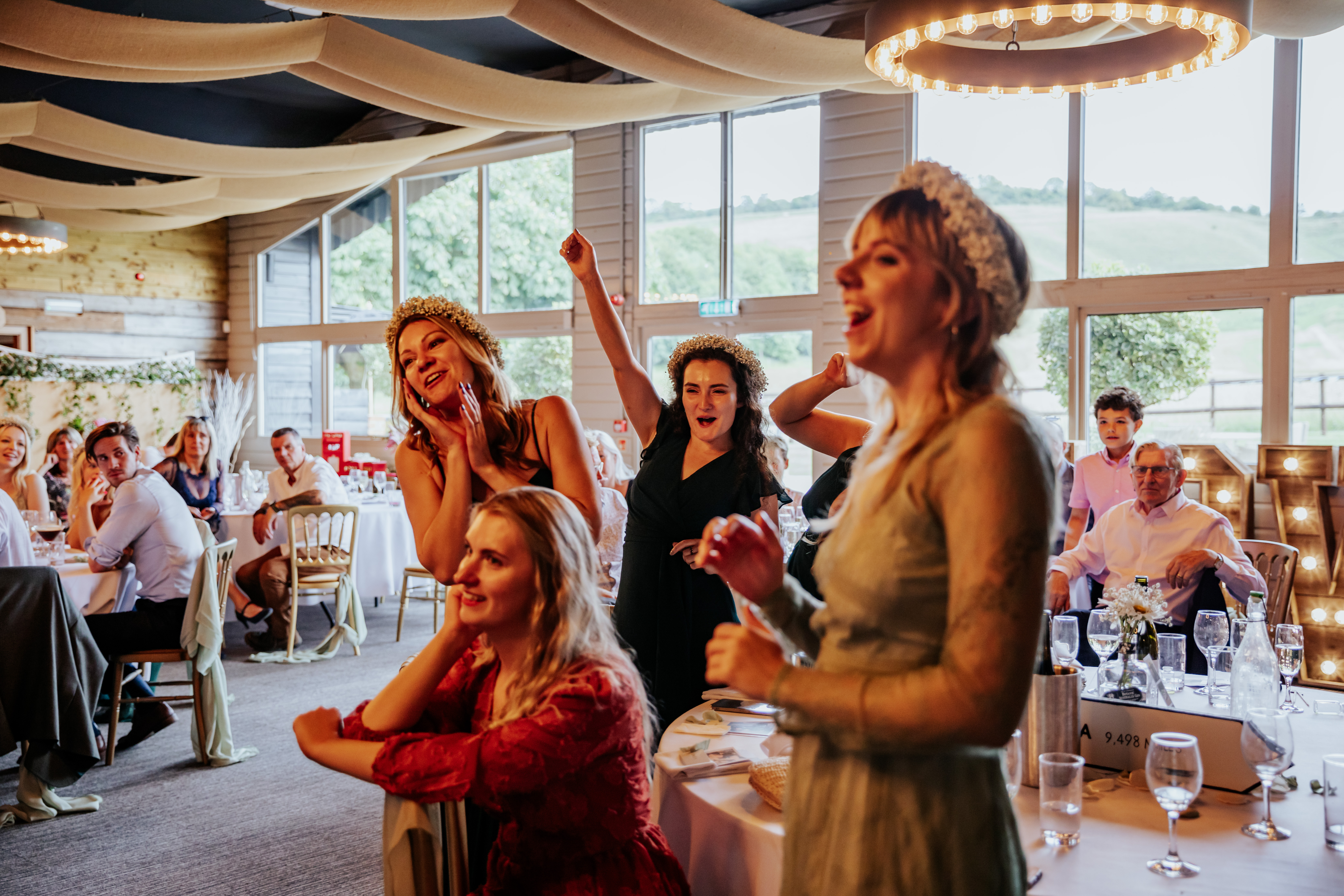 A table of bridesmaids stand up and cheer during a speech