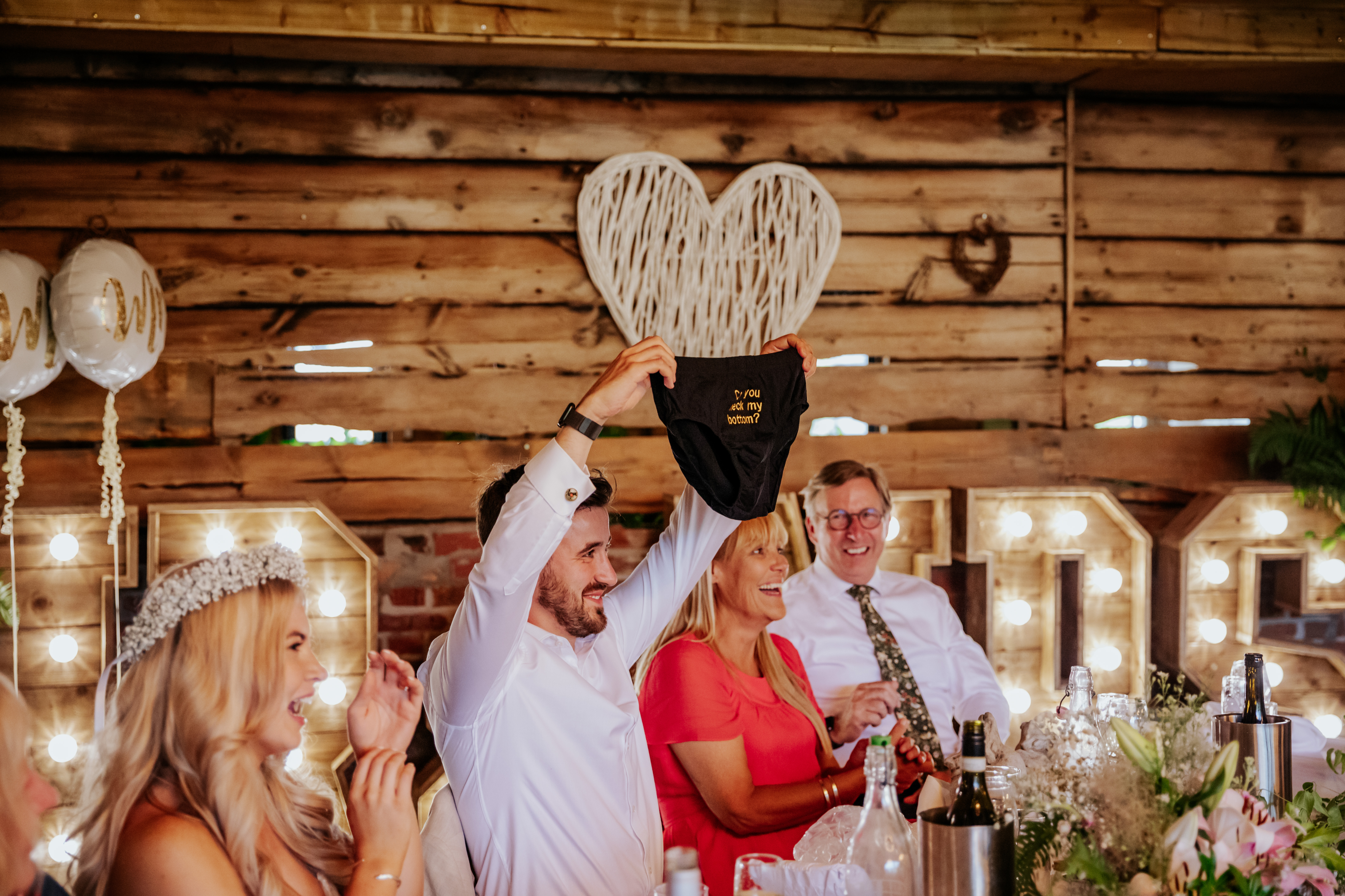 The groom holds up a small paid of briefs that say 'can you check my bottom?' on them