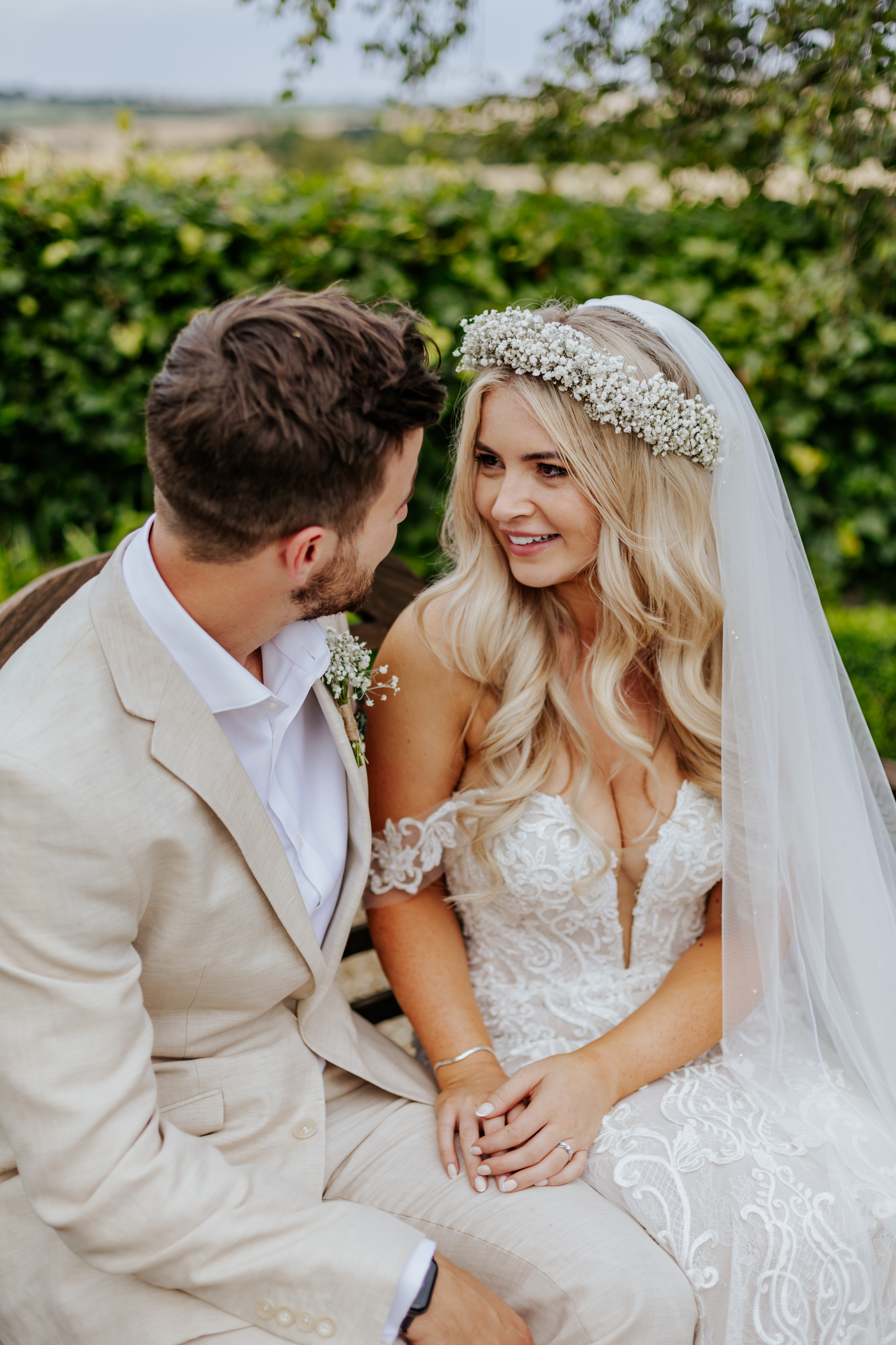 Bride and groom sit on a bench together, smiling